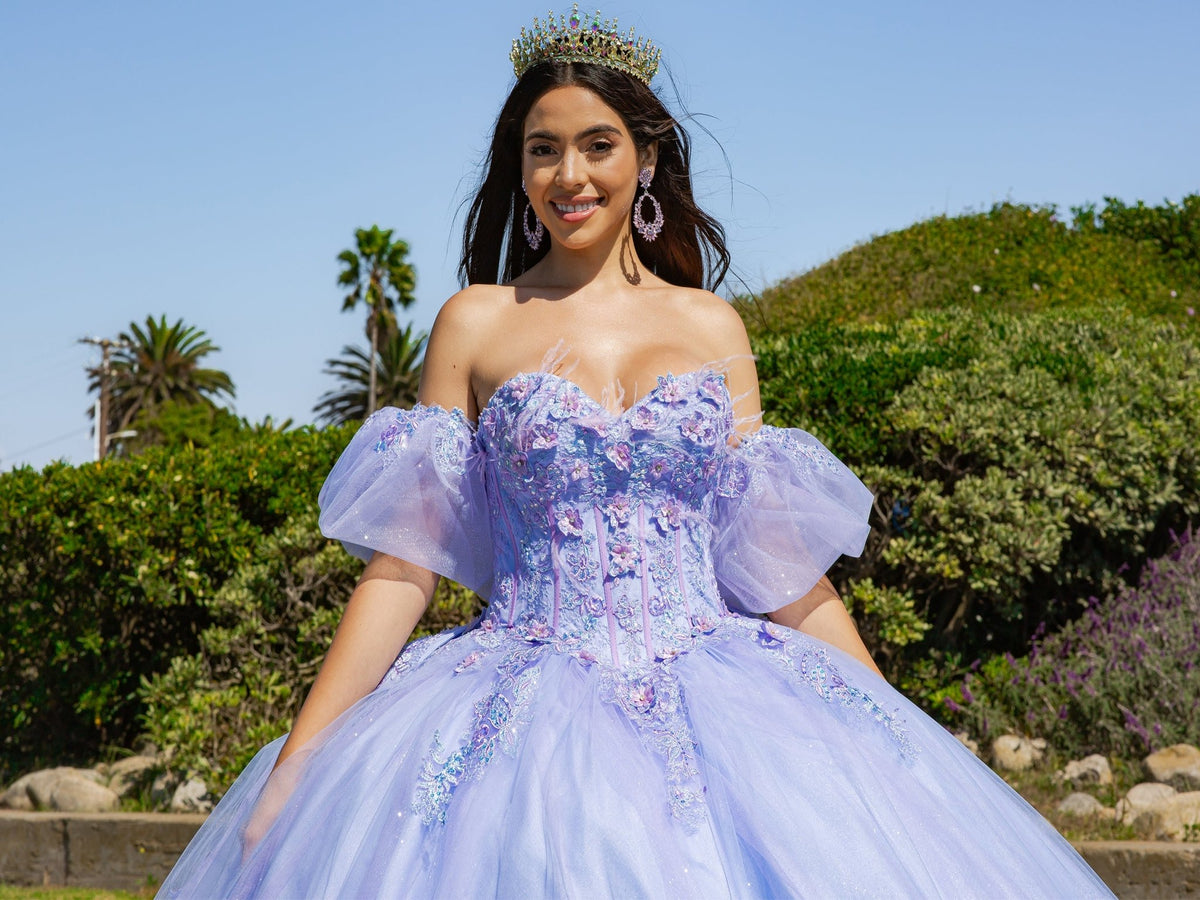 Close-up view reveals lilac two-tone quinceanera ball gown with floral embroidery, puff sleeves, and glitter tulle fabric.
