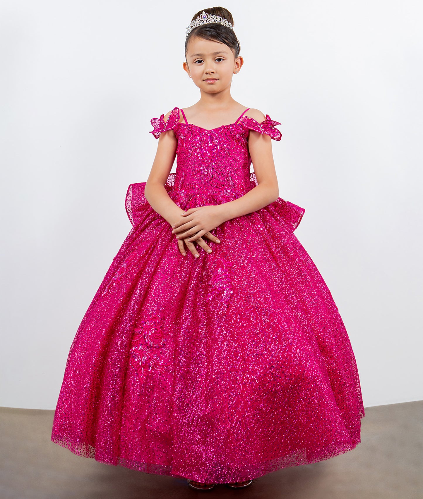 Young girl wearing a pink sparkly dress against a white background