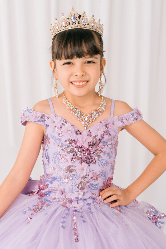 Young girl in a floral mini quince dress with a tiara and necklace against a white background
