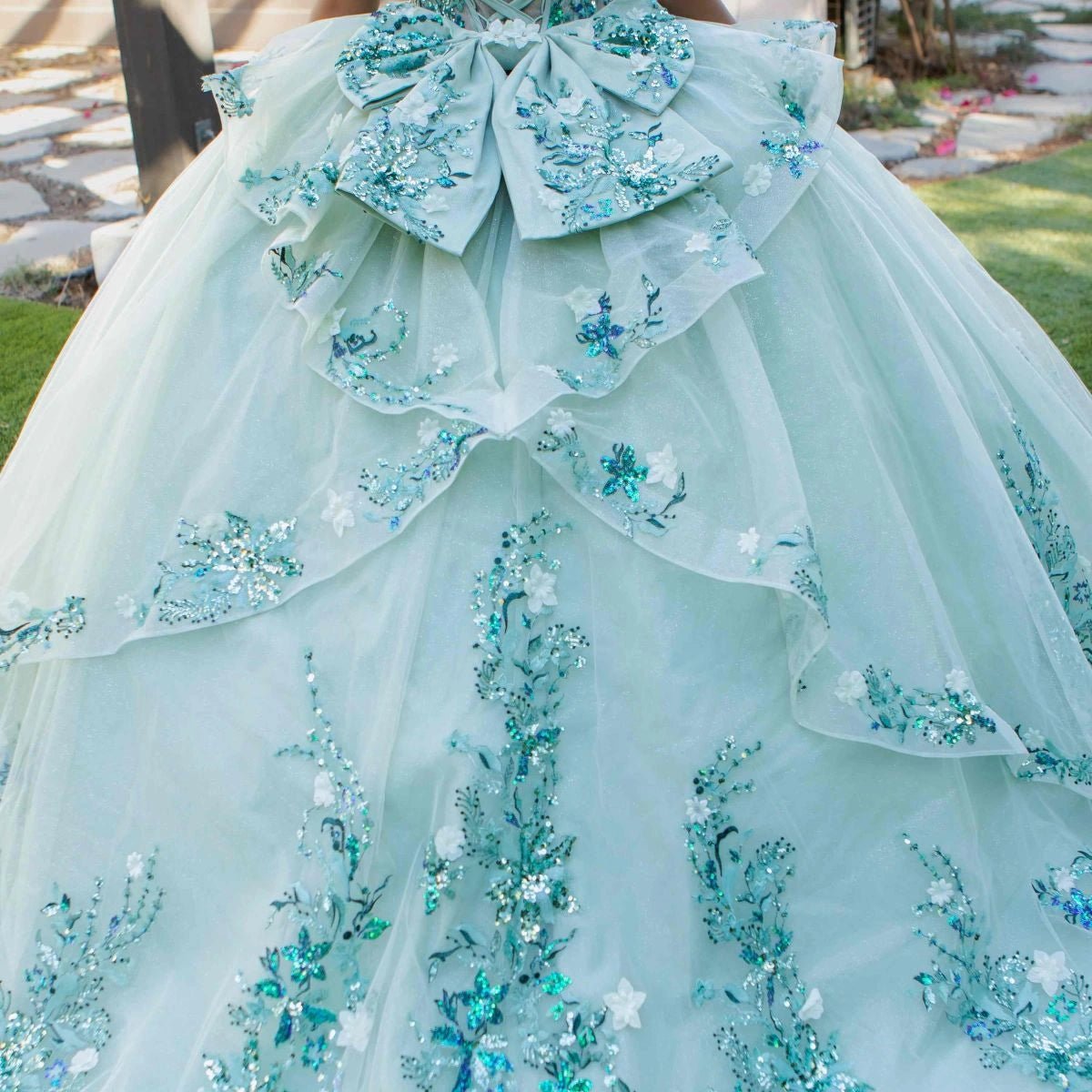 Displayed in a back detail, the Sage quinceañera dress has oversized floral bow and three-dimensional flowers across the skirt.