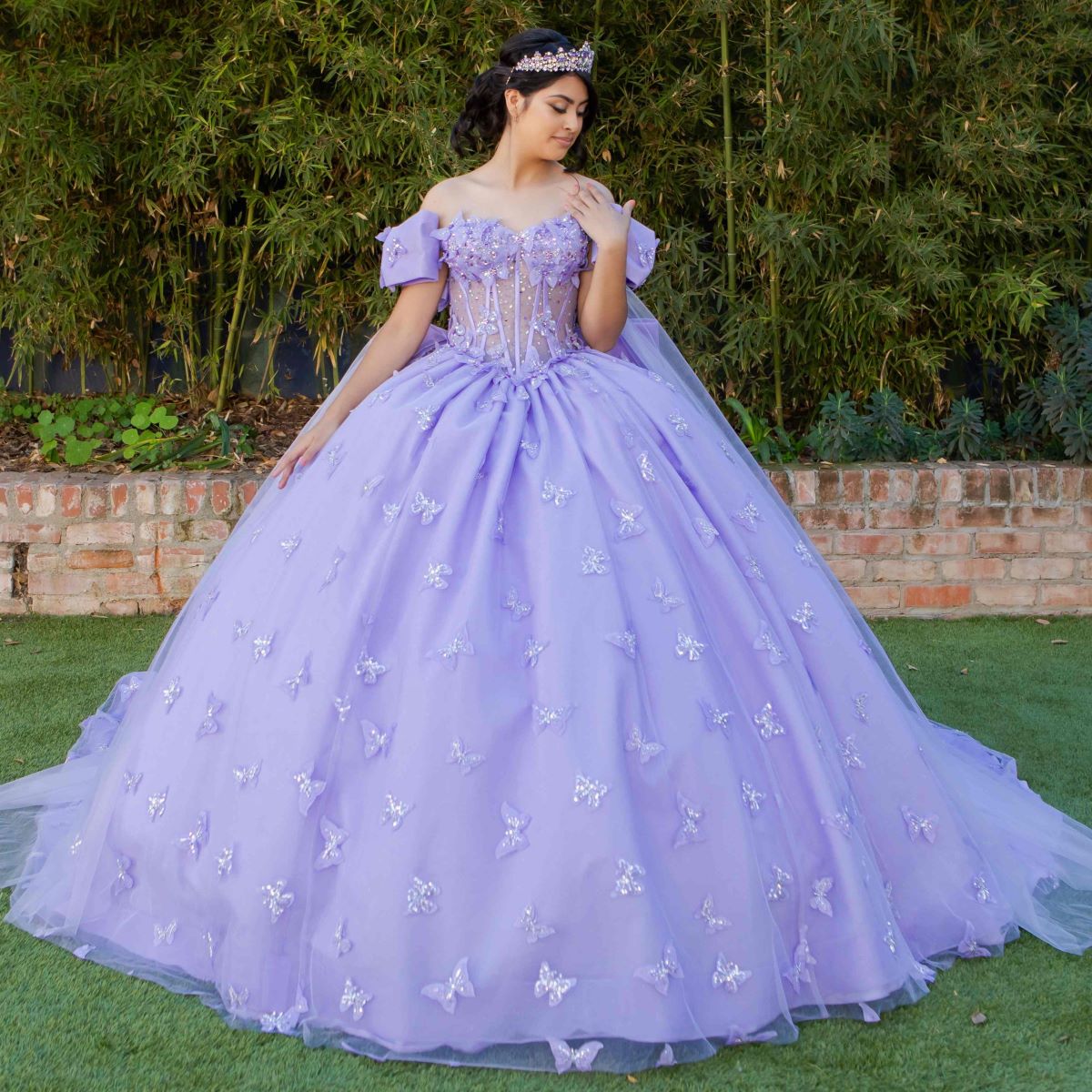 Skirt detail shows lilac quinceanera ball gown with butterfly appliques, puffed sleeves, and glitter tulle skirt.