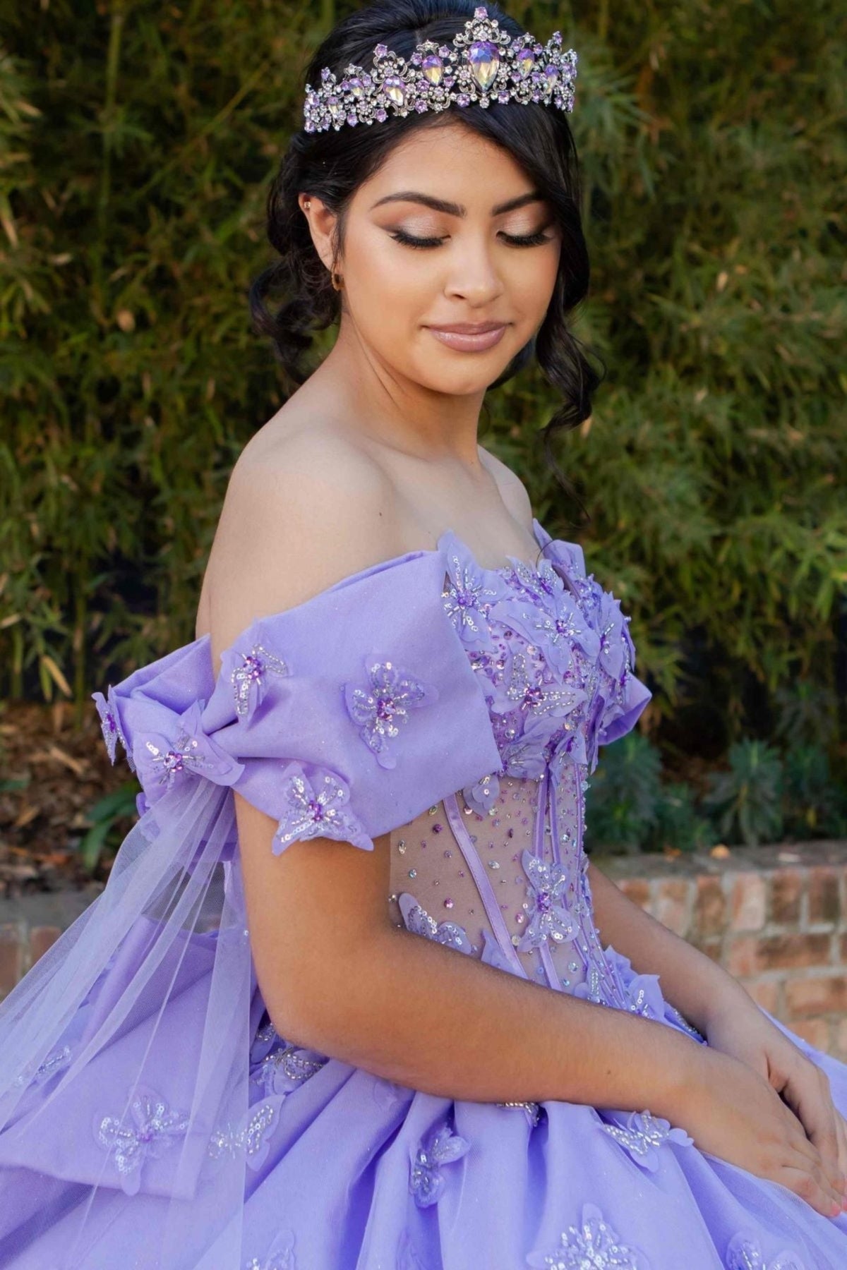 Close-up view reveals zoomed a lilac quinceanera ball gown with butterfly appliques, puffed sleeves, and glitter tulle fabric.