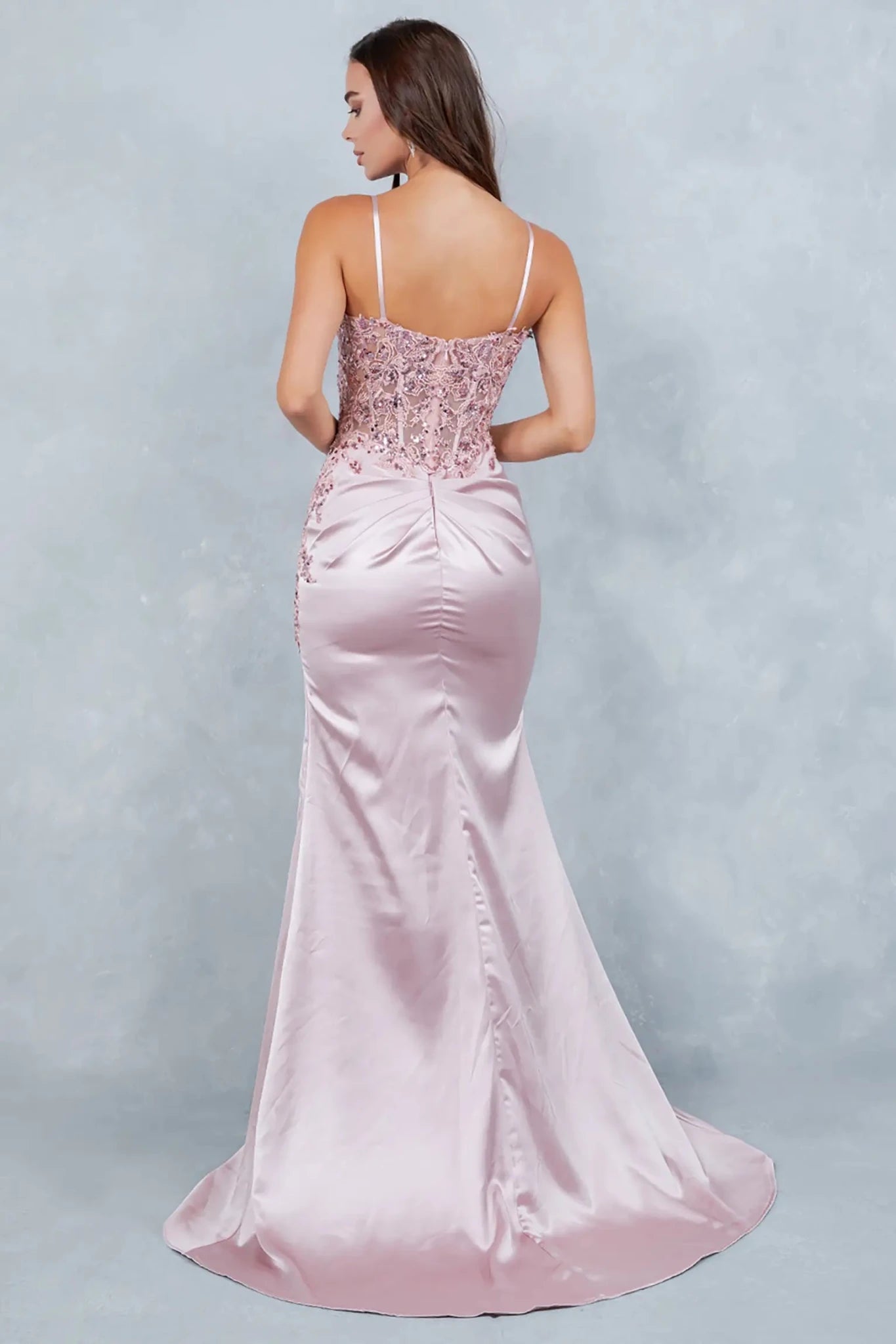 A full back view of a woman wearing a rose gold satin dress with an elegant silhouette.