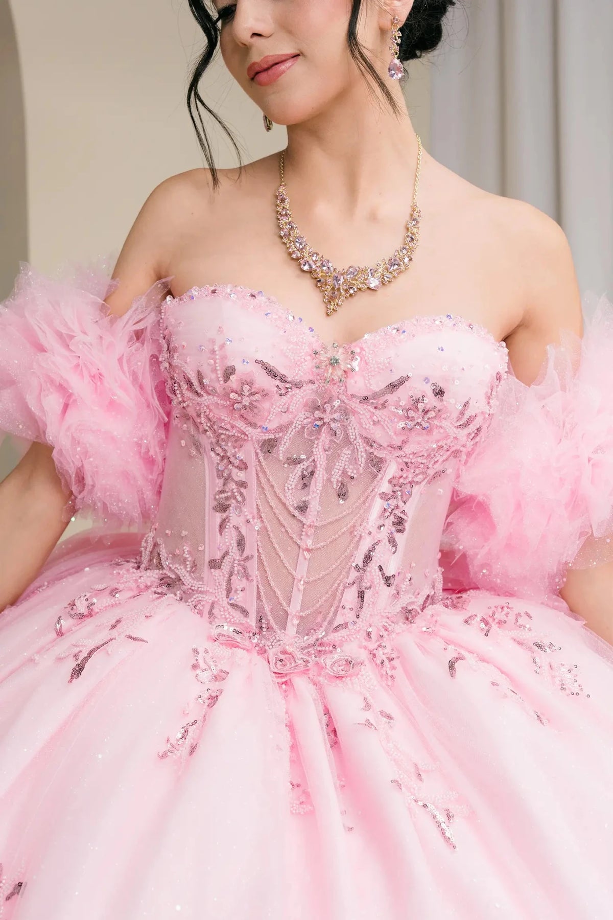 Close-up view reveals Pink quinceanera dress with upper bodice and jewelry detail view: Close-up of pink quinceañera gown.