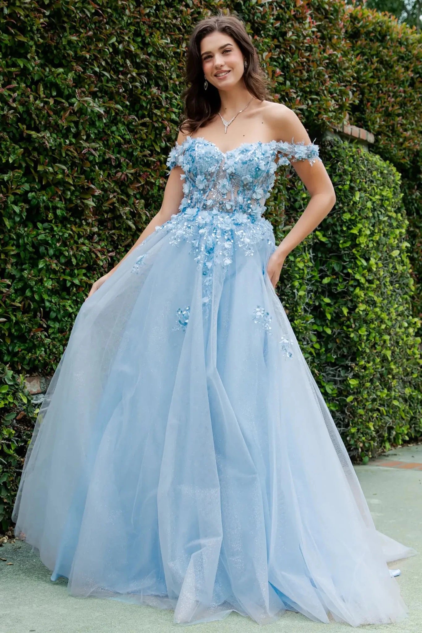 Full-length front view of a woman wearing a blue fairytale prom dress featuring a lace-up corset and layered tulle skirt.