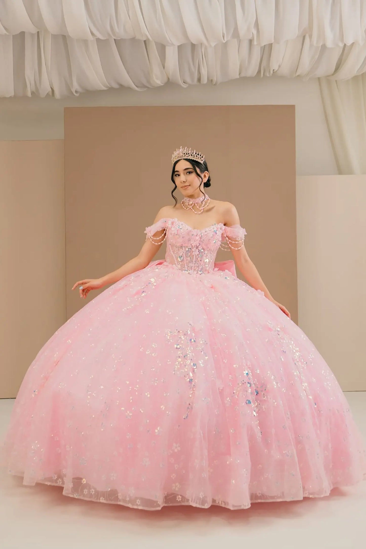 Full front view of a woman wearing pink quinceañera dress with glitter tulle skirt, off-shoulder sweetheart neckline, and beaded corset bodice.