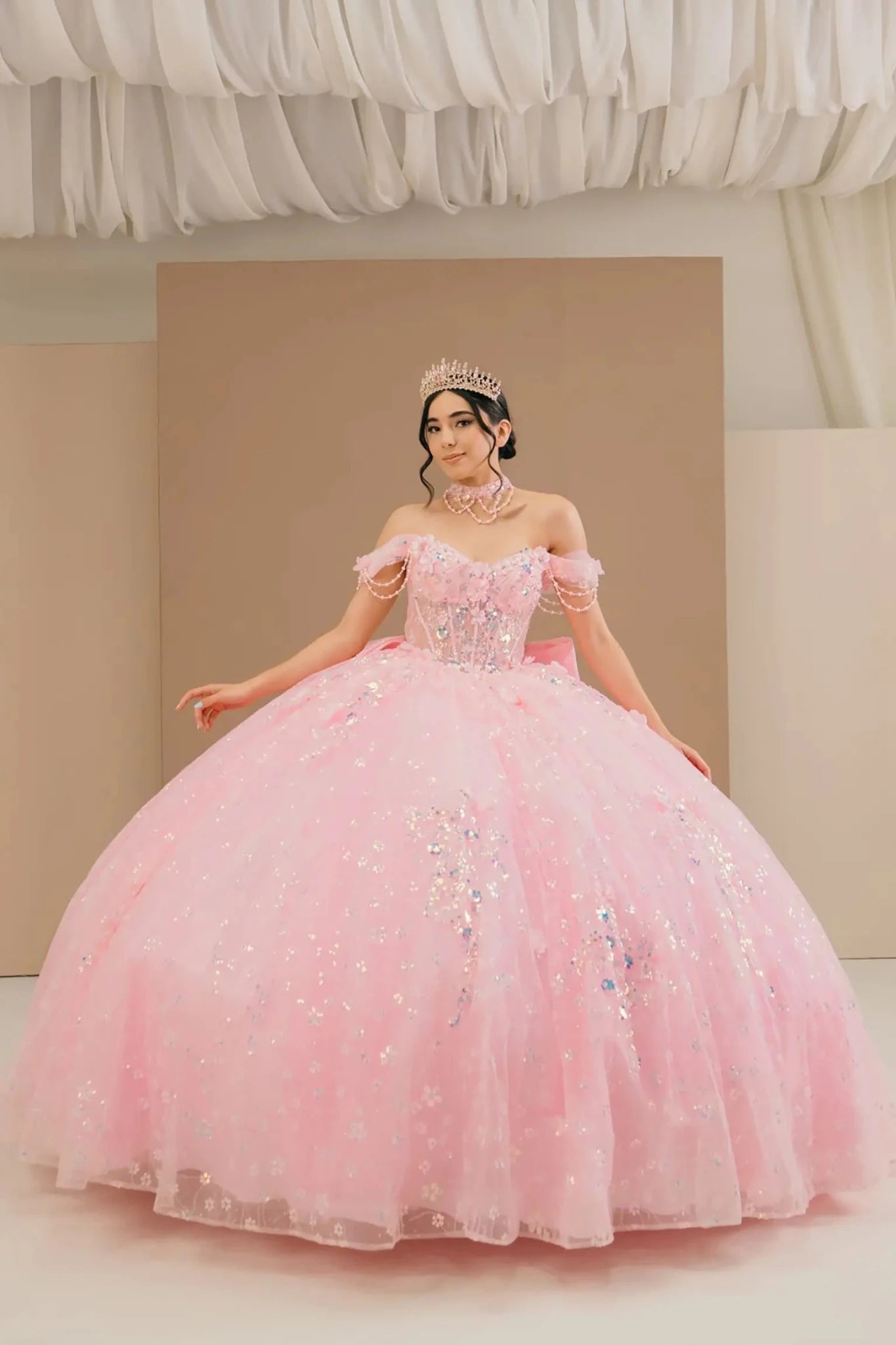 Full front view of a woman wearing pink quinceañera dress with glitter tulle skirt, off-shoulder sweetheart neckline, and beaded corset bodice.