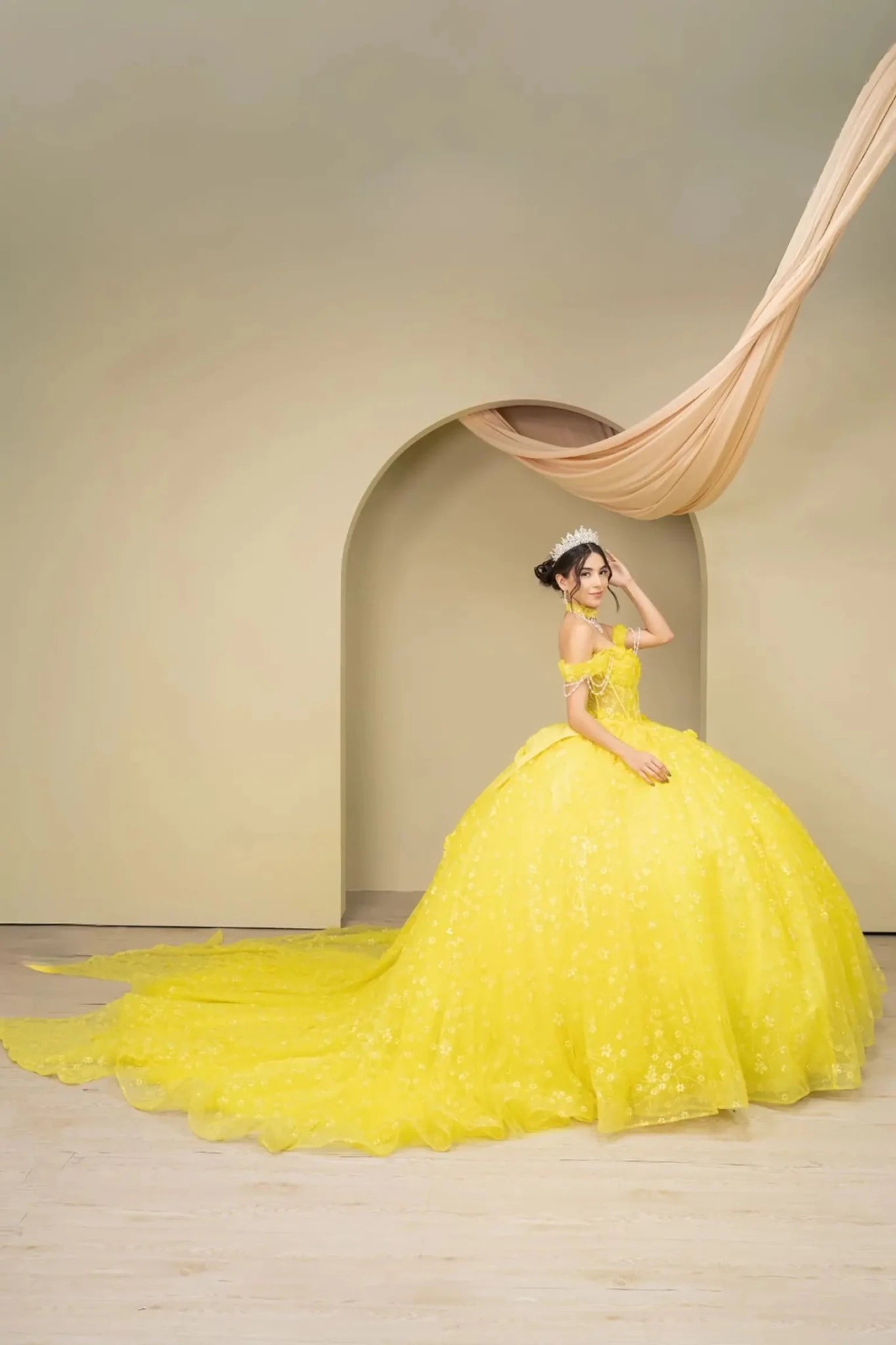 Full side view of a woman wearing yellow quinceañera dress with glitter tulle skirt, sweetheart neckline, and beaded corset bodice.