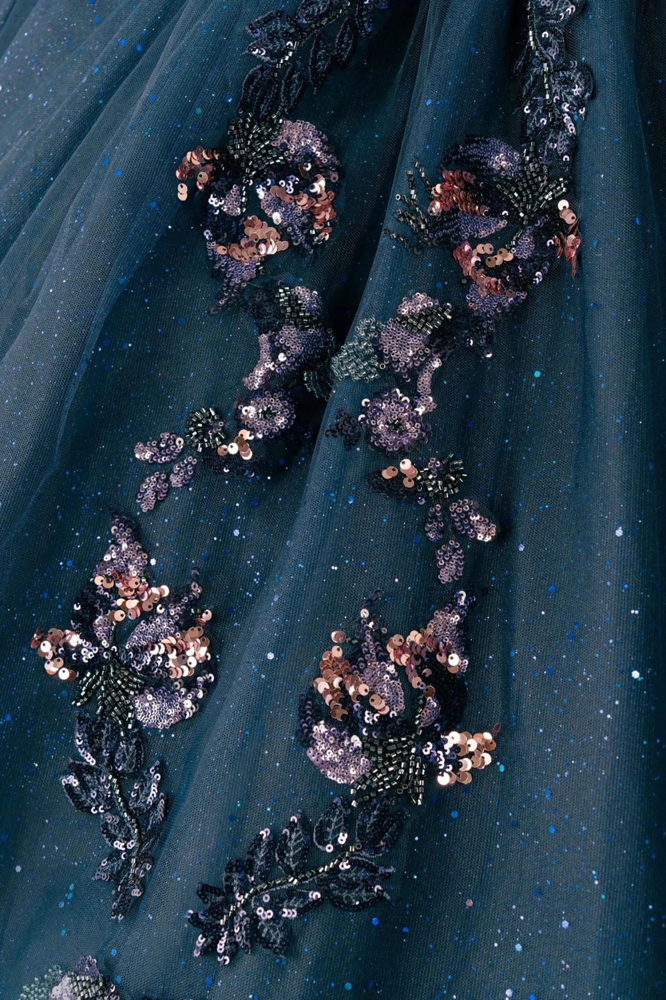 Close-up of navy quinceañera royal dress lower skirt with shimmering textured tulle layers, cathedral train, and glitter accents