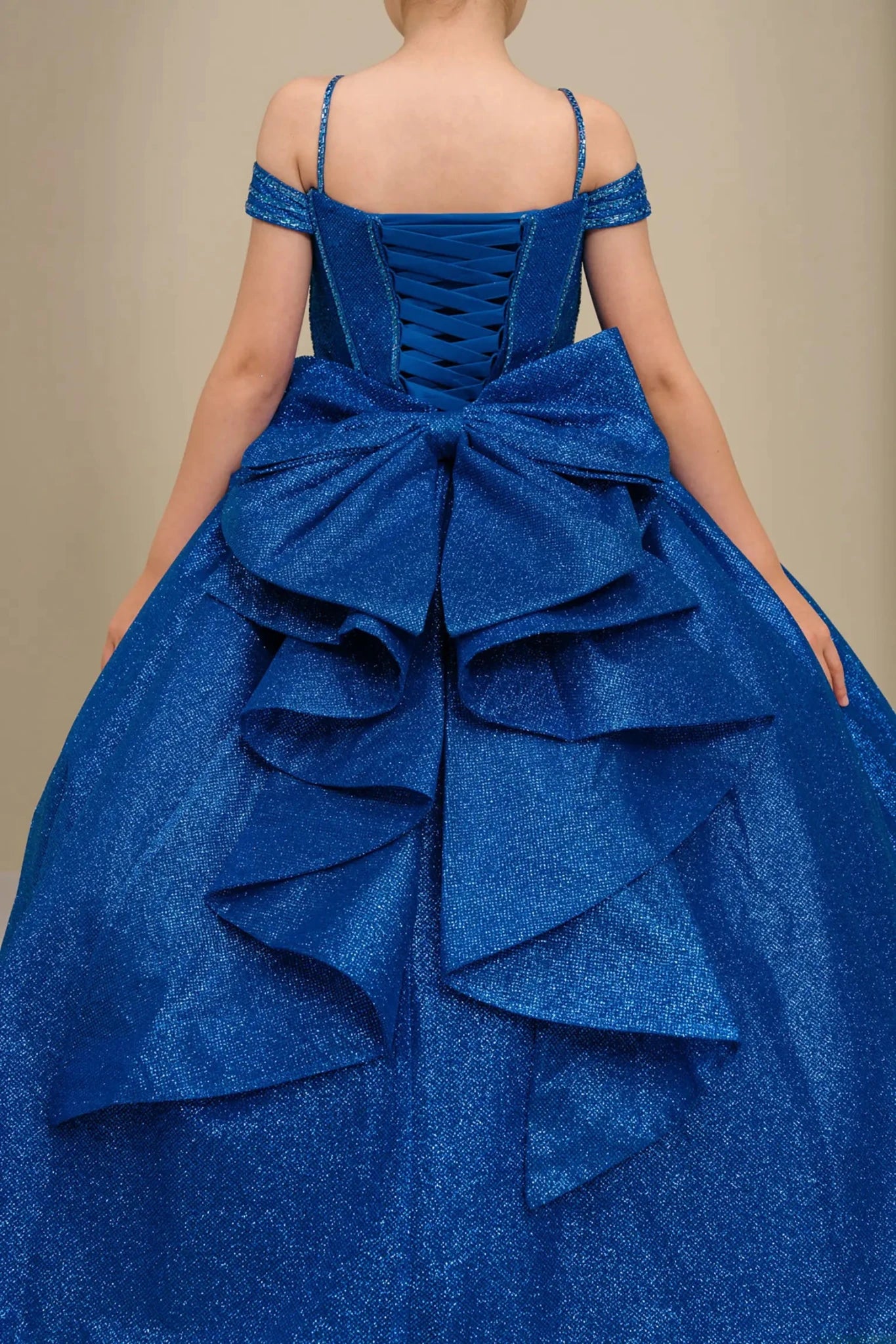 Close-up of royal blue mini quince dress fabric with shimmering tulle layers and oversized tiered bow detailing.