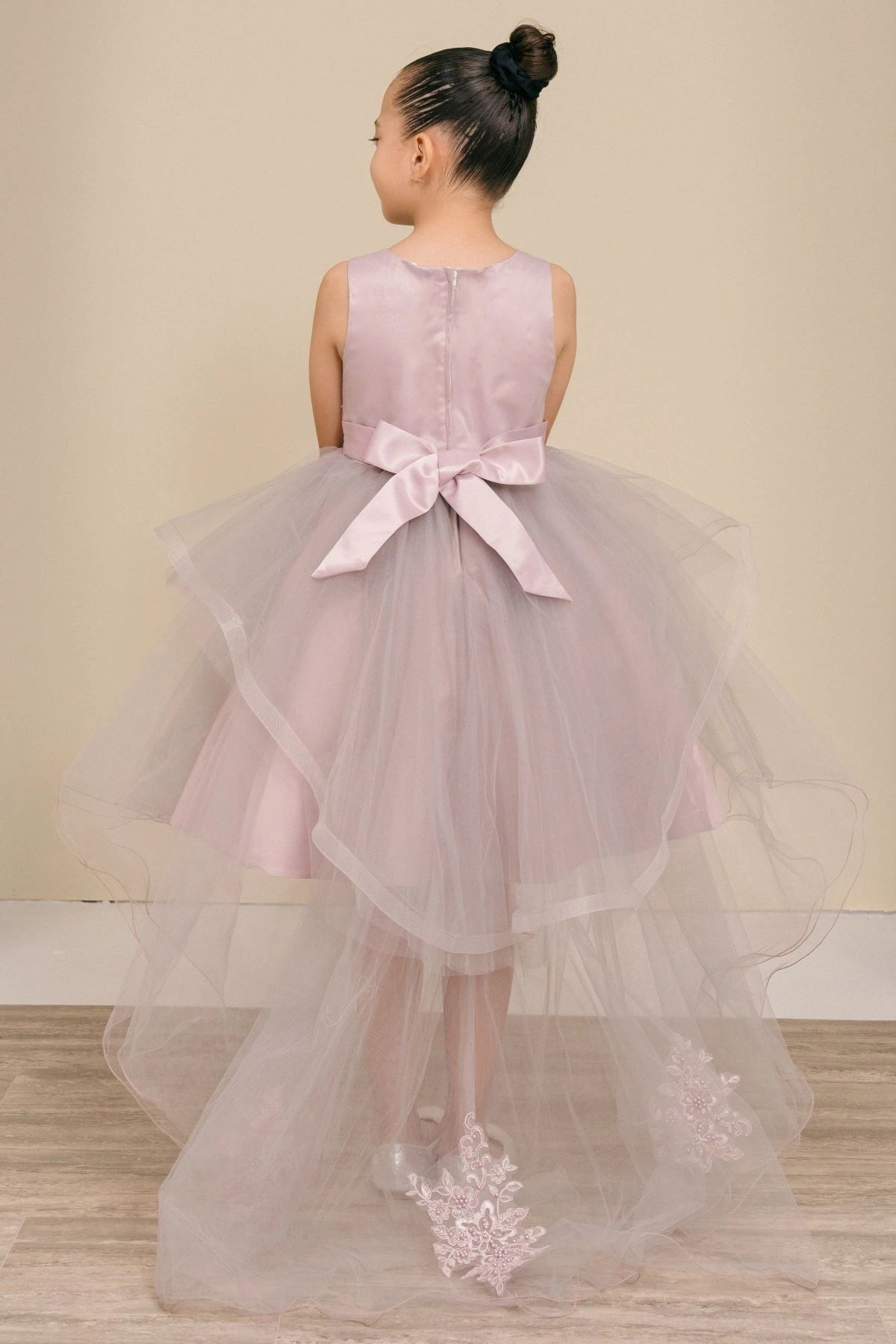 Shown in a back view, the Mauve flower girl dress has satin bow and sheer tulle skirt with lace train appliques.
