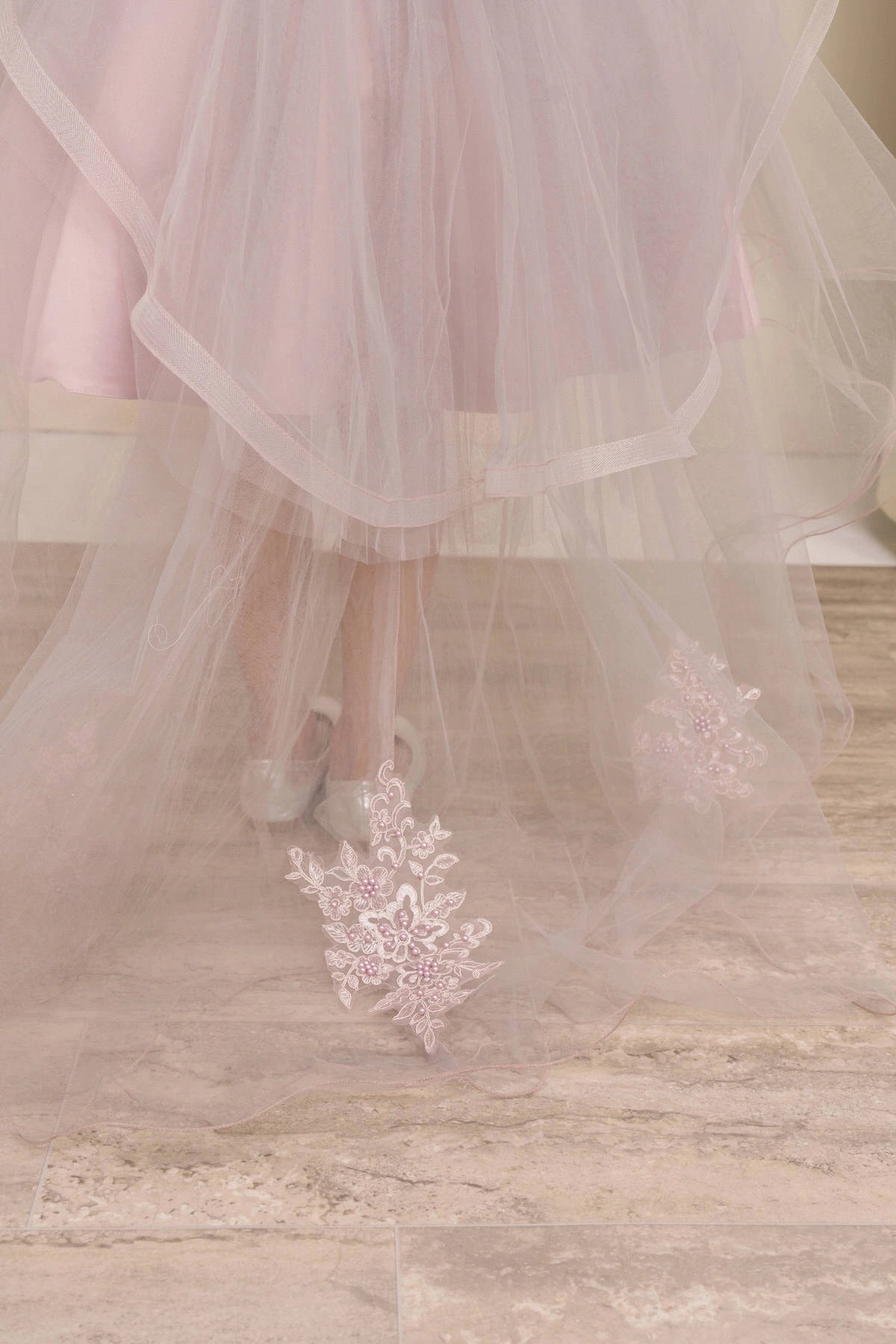 Displayed in a skirt detail, the Mauve flower girl dress has layered tulle hem and lace appliques on the trailing skirt.