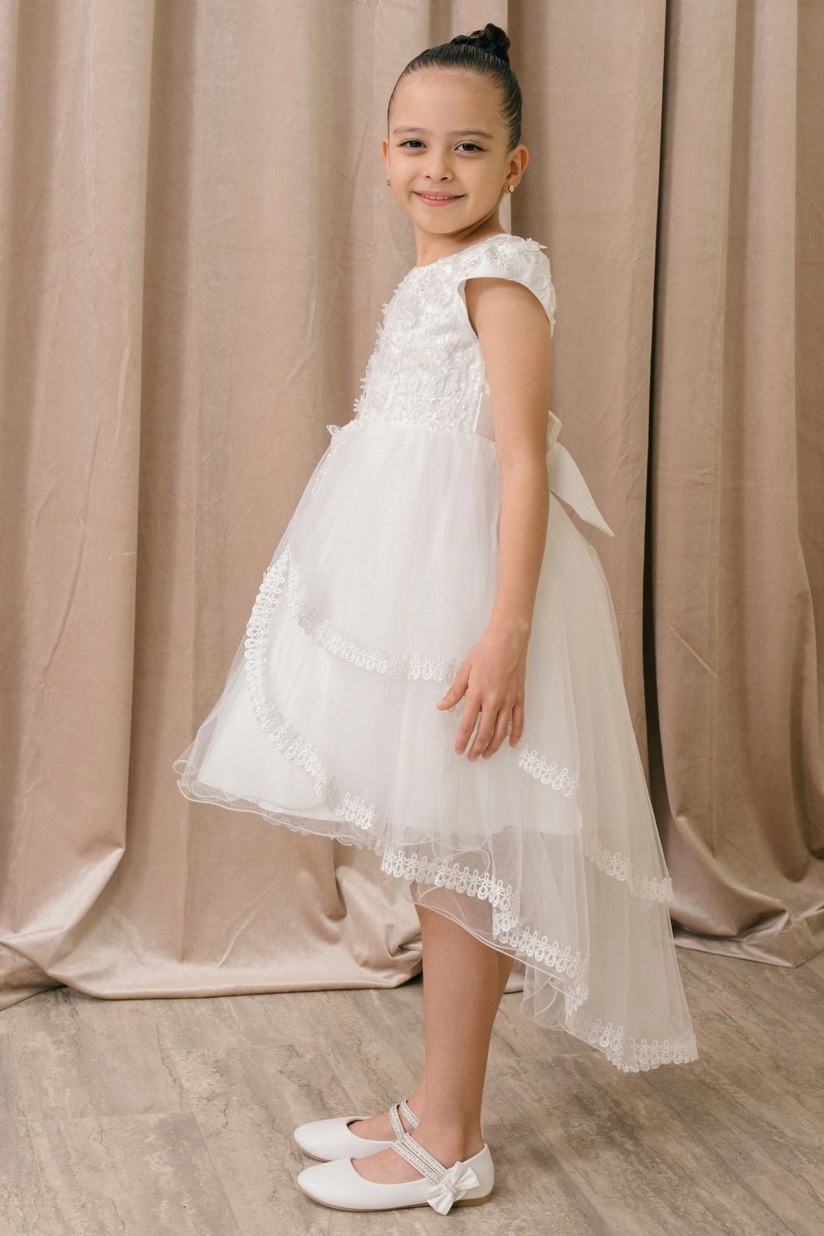 Featuring scalloped lace tiers with a long back hem on the White flower girl dress.