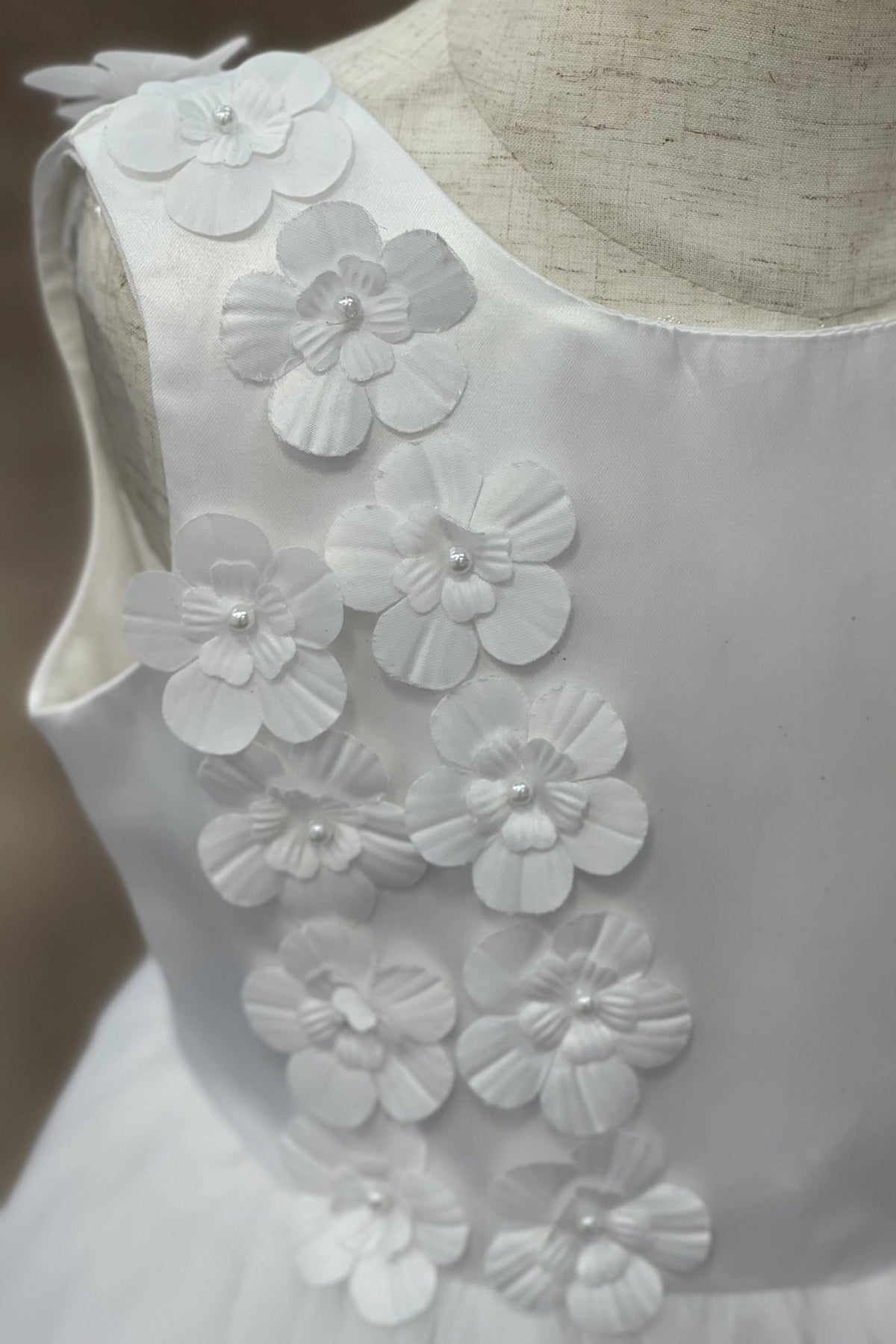 Featuring dimensional fabric flowers along the neckline on the White flower girl dress.