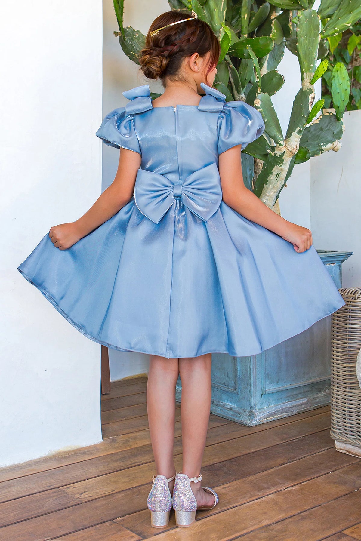 A Blue flower girl dress showing satin back bow below the puff sleeves.