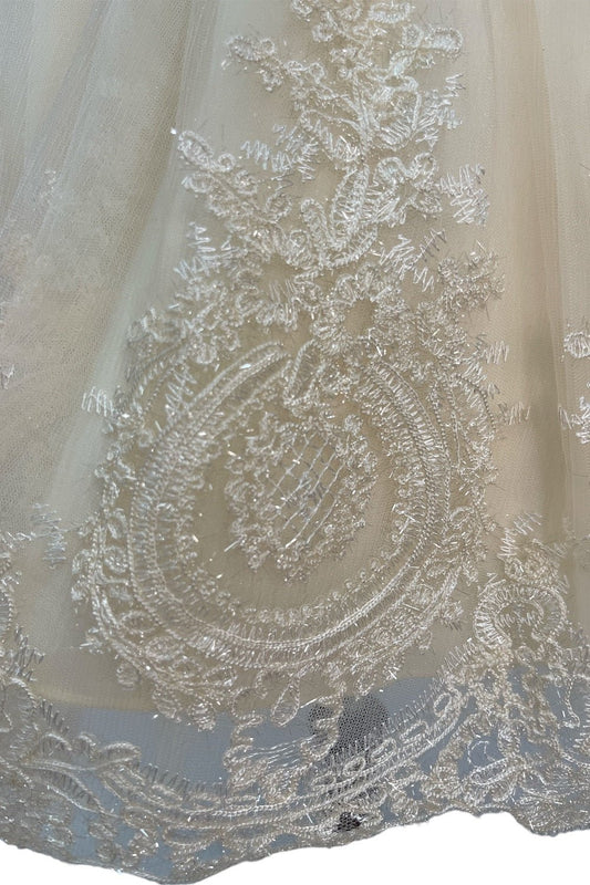 Close-up front view of cream dress showing shimmering fabric and bow accent