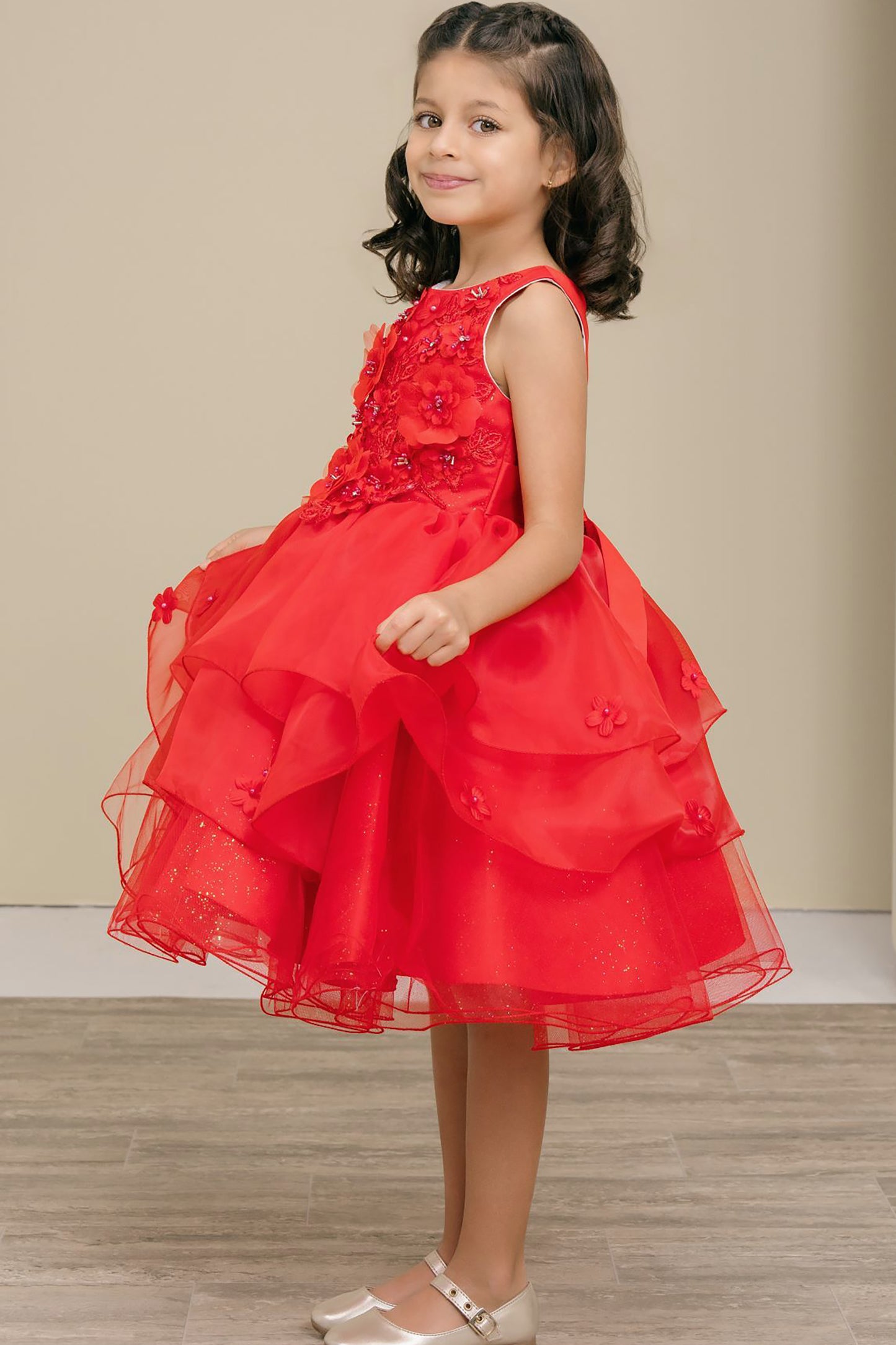 Young girl wearing a red dress with floral details on a neutral background