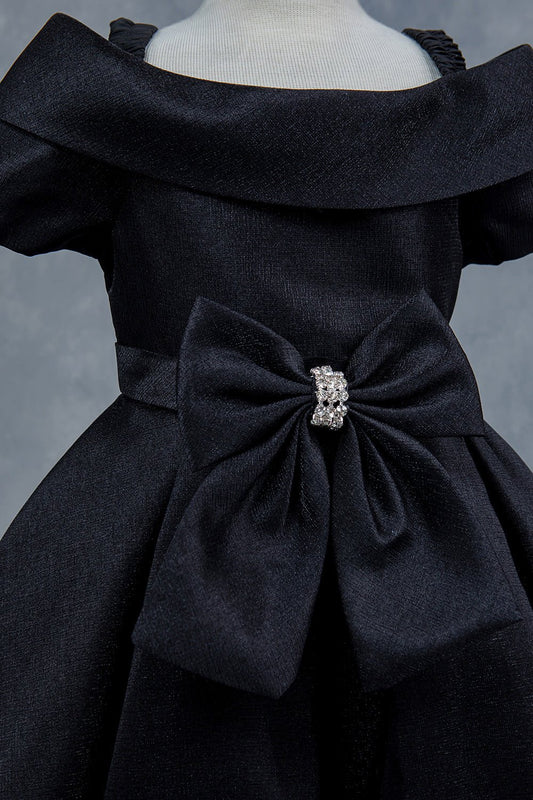 Close-up front view of black dress showing rhinestone bow detail and collar