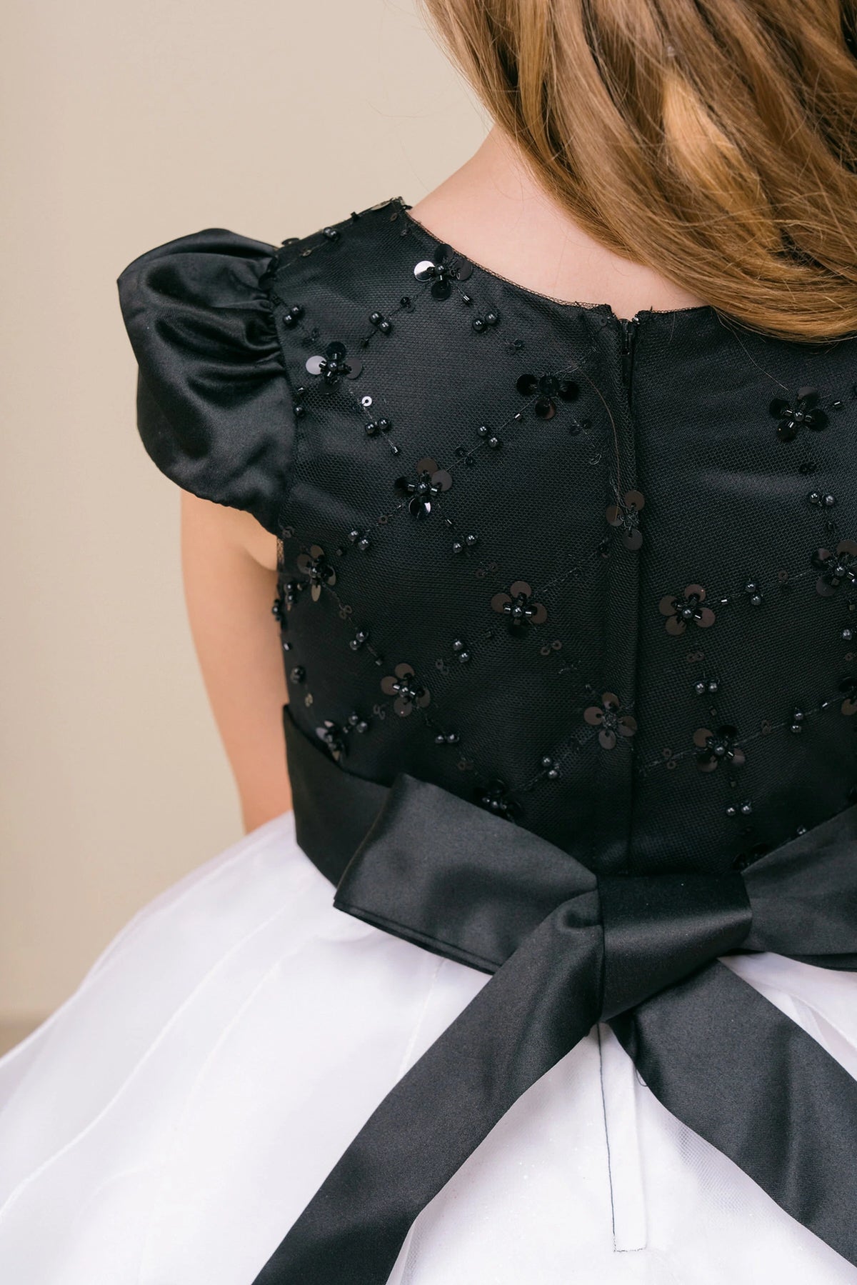 Beaded floral details cover the upper back of this Black/White kids party dress.
