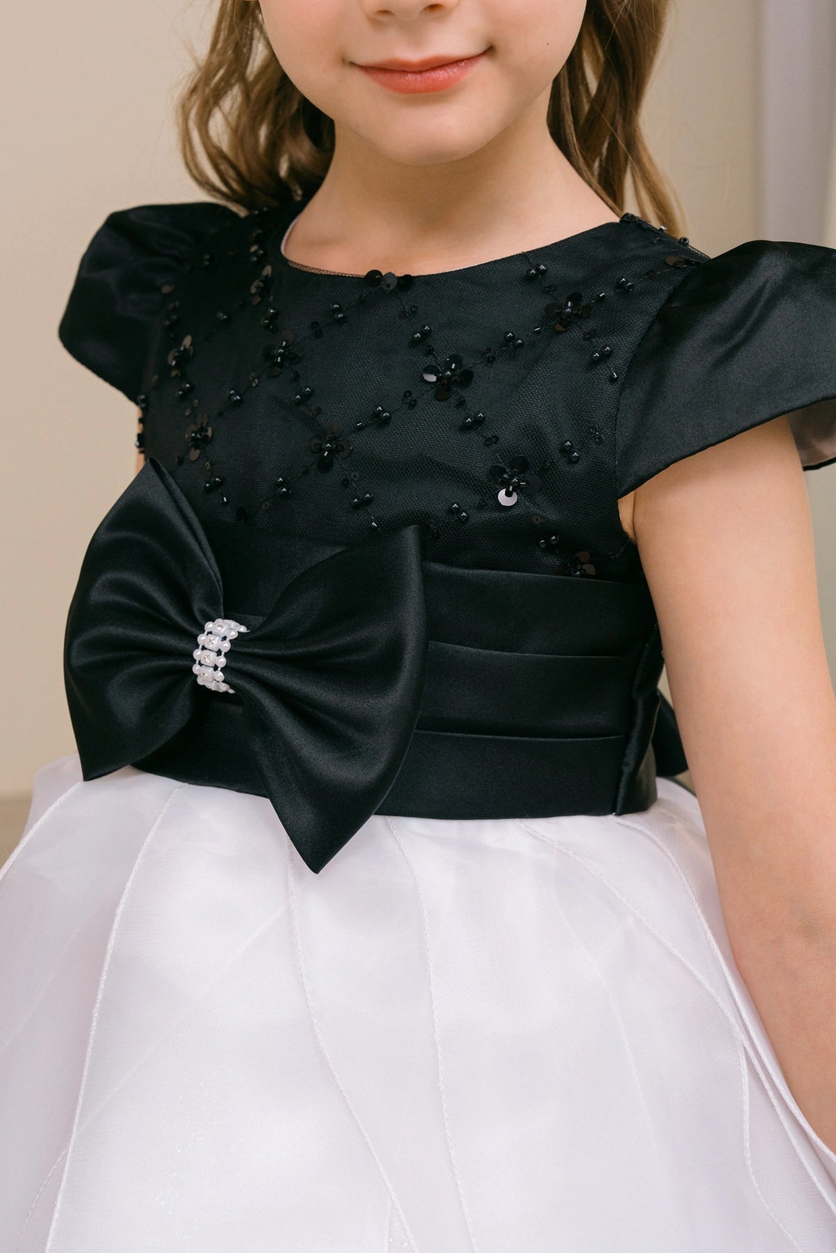Embellished bow centers the satin waistband of the Black/White kids party dress.