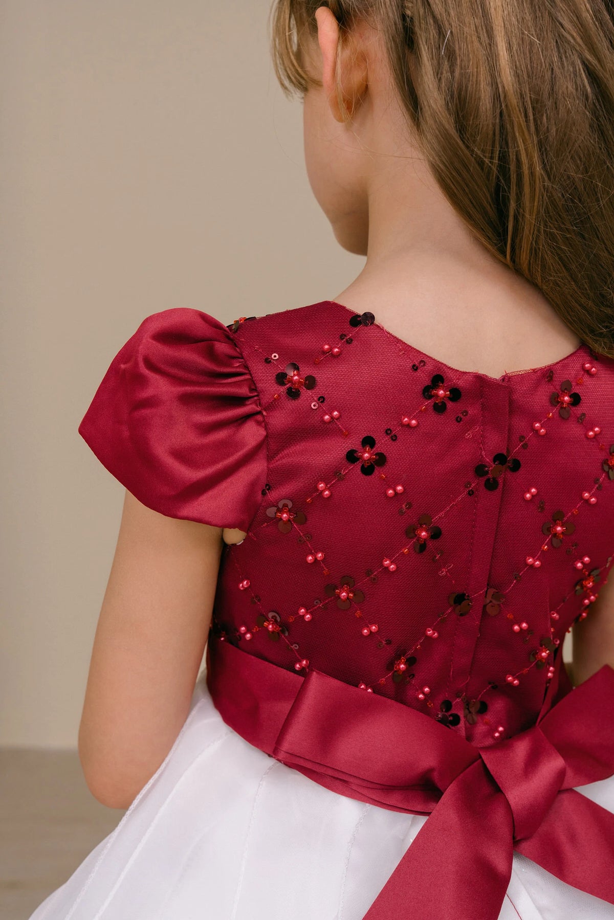 Gathered puff sleeves frame the embellished back of the Burgundy/Ivory kids party dress.
