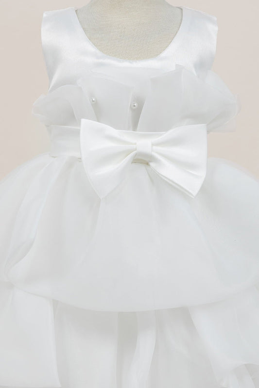 Close-up front view of white dress showing shimmering fabric and bow accent
