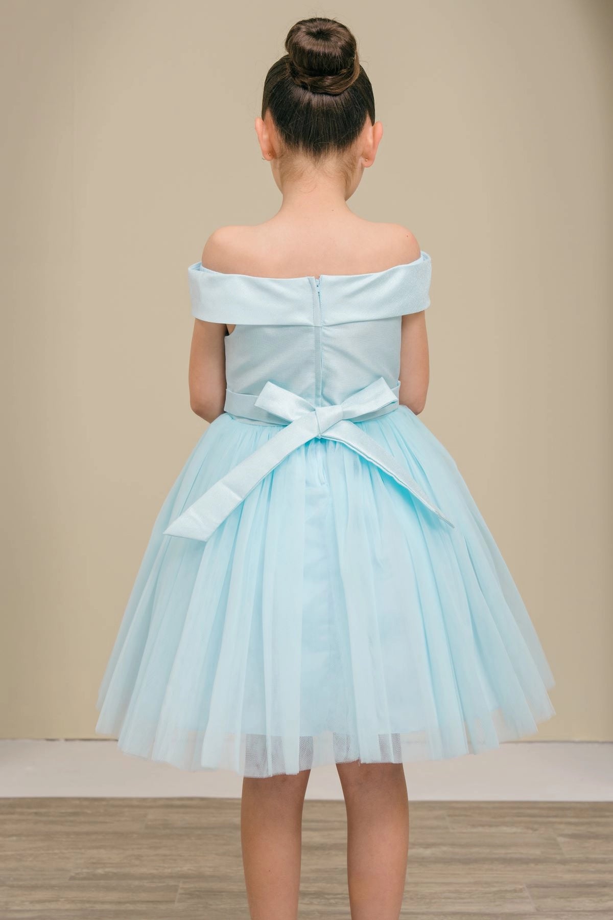 A Blue flower girl dress showing back sash bow below the off-shoulder band.