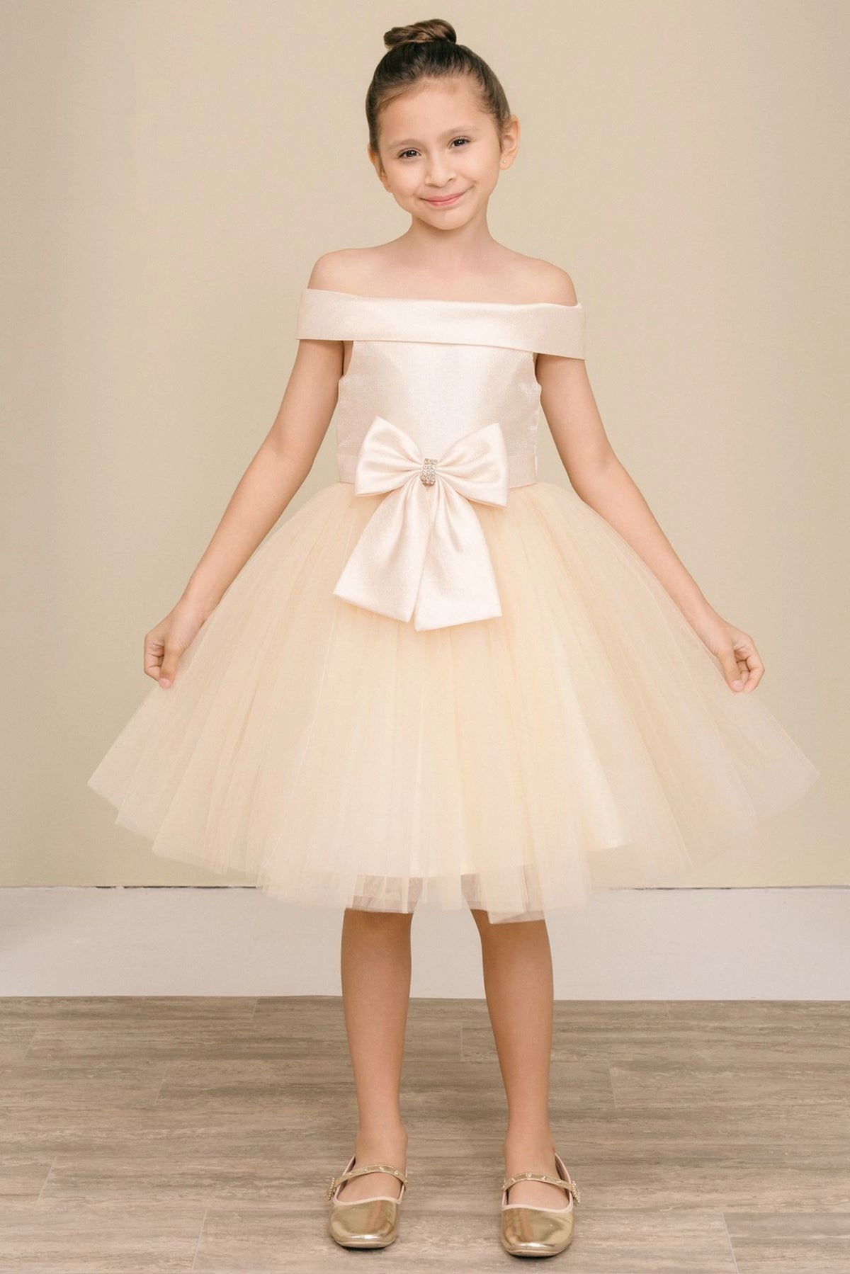 Champagne flower girl dress features large front bow above the layered tulle skirt.