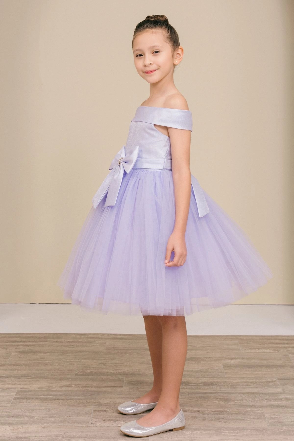 Featuring large front bow beside a flared tulle skirt on the Lilac flower girl dress.