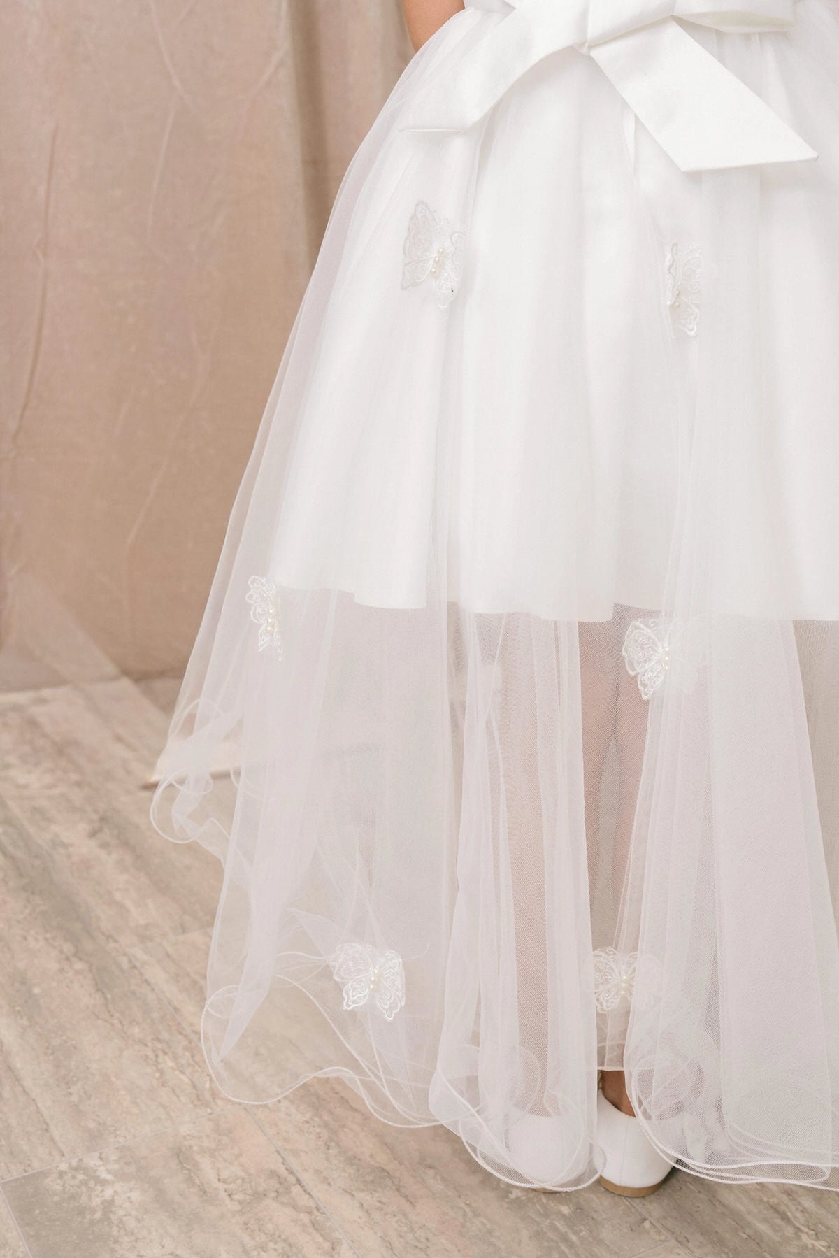 Designed details of a tiered high-low skirt distinguish the White kids party dress.