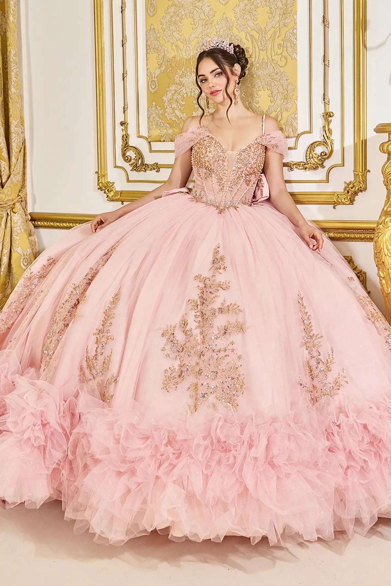Standing front view of blush quinceañera ball gown with structured beaded bodice, sheer neckline detail, and full layered tulle skirt with ornate applique accents