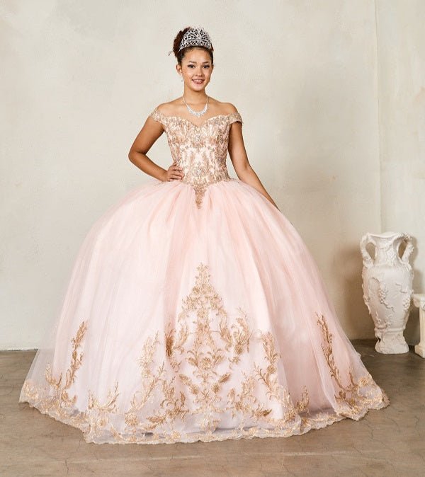 A woman standing in a elegant off-the-shoulder pink quinceañera gown with embroidered lace appliques and glitter tulle overlay, posing against a neutral background.