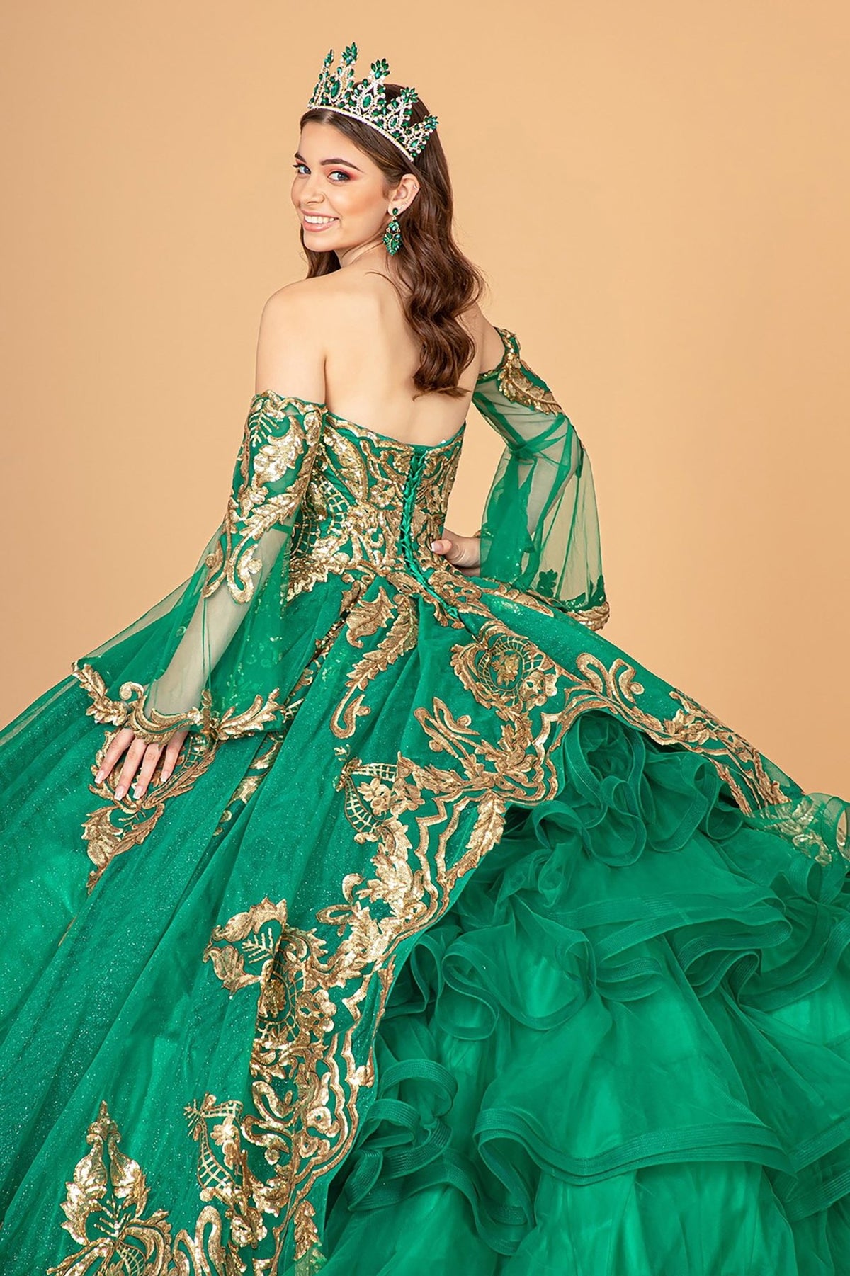 Back zoom view of a woman wearing emerald green quinceañera dress with sequin embellishments and glitter mesh skirt