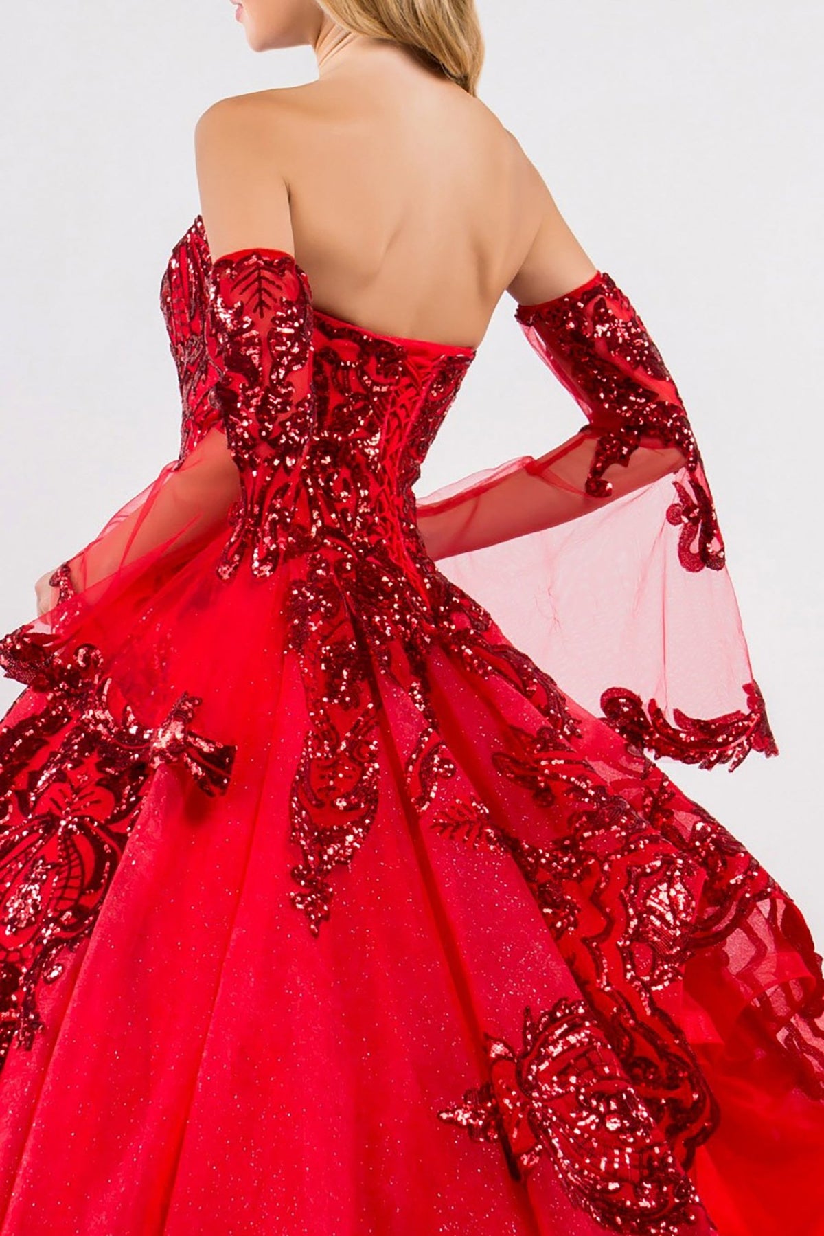 Back view of a woman wearing red quinceañera dress with sequin embellishments and glitter mesh skirt