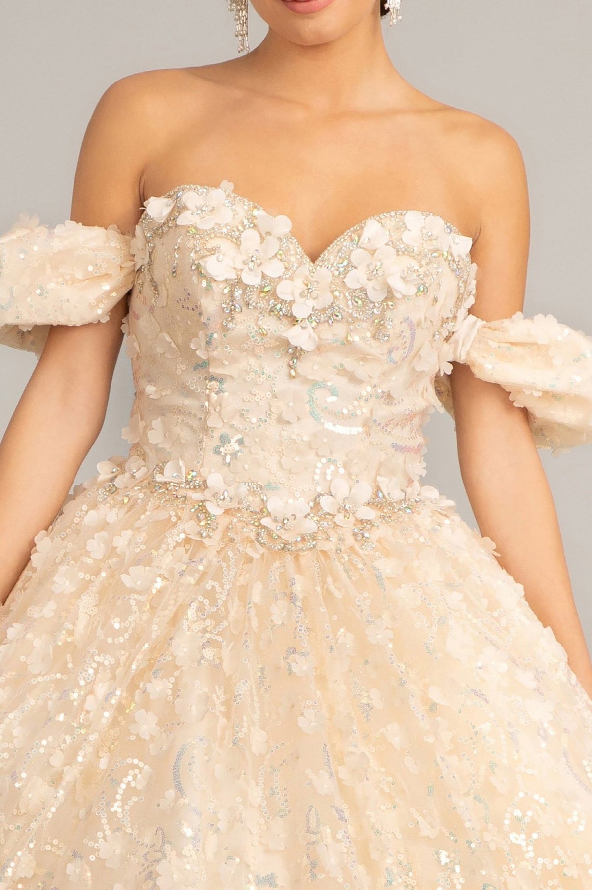 Bodice close-up highlights a champagne quinceañera dress with jewel embellishments and 3D appliques.