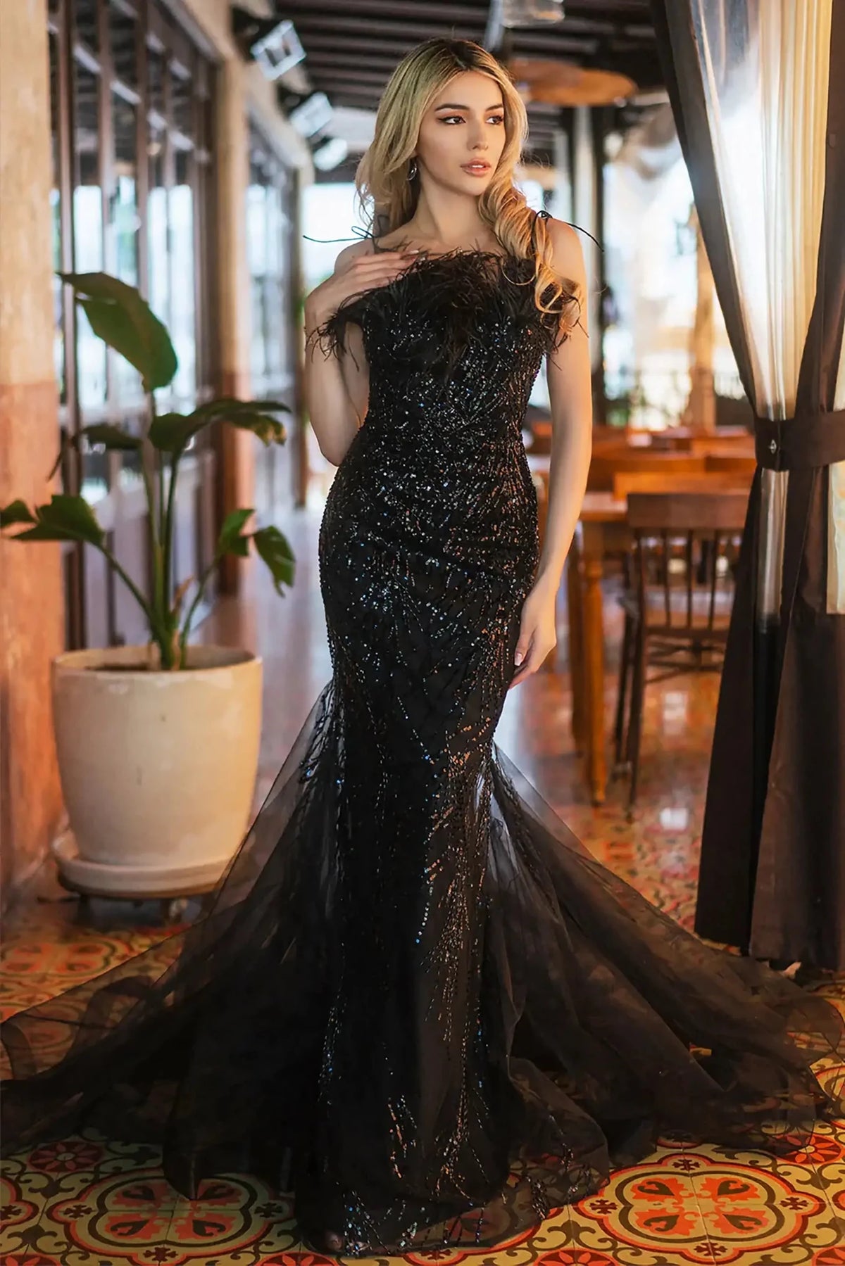 Full-length view highlights a Black sequin sweetheart trumpet prom dress with feather embellishments.