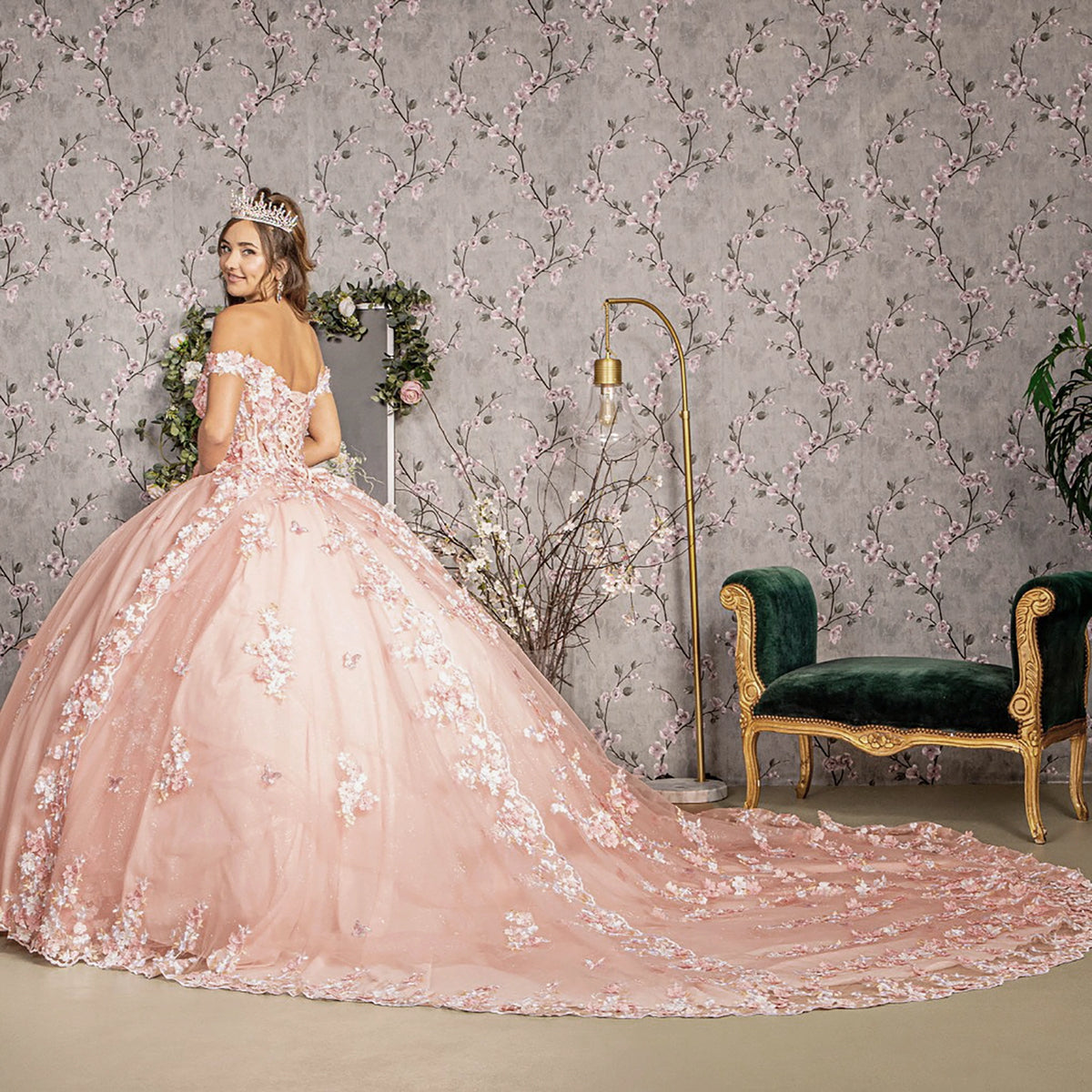Side profile shows blush quinceañera dress with 3D floral appliques and long train.