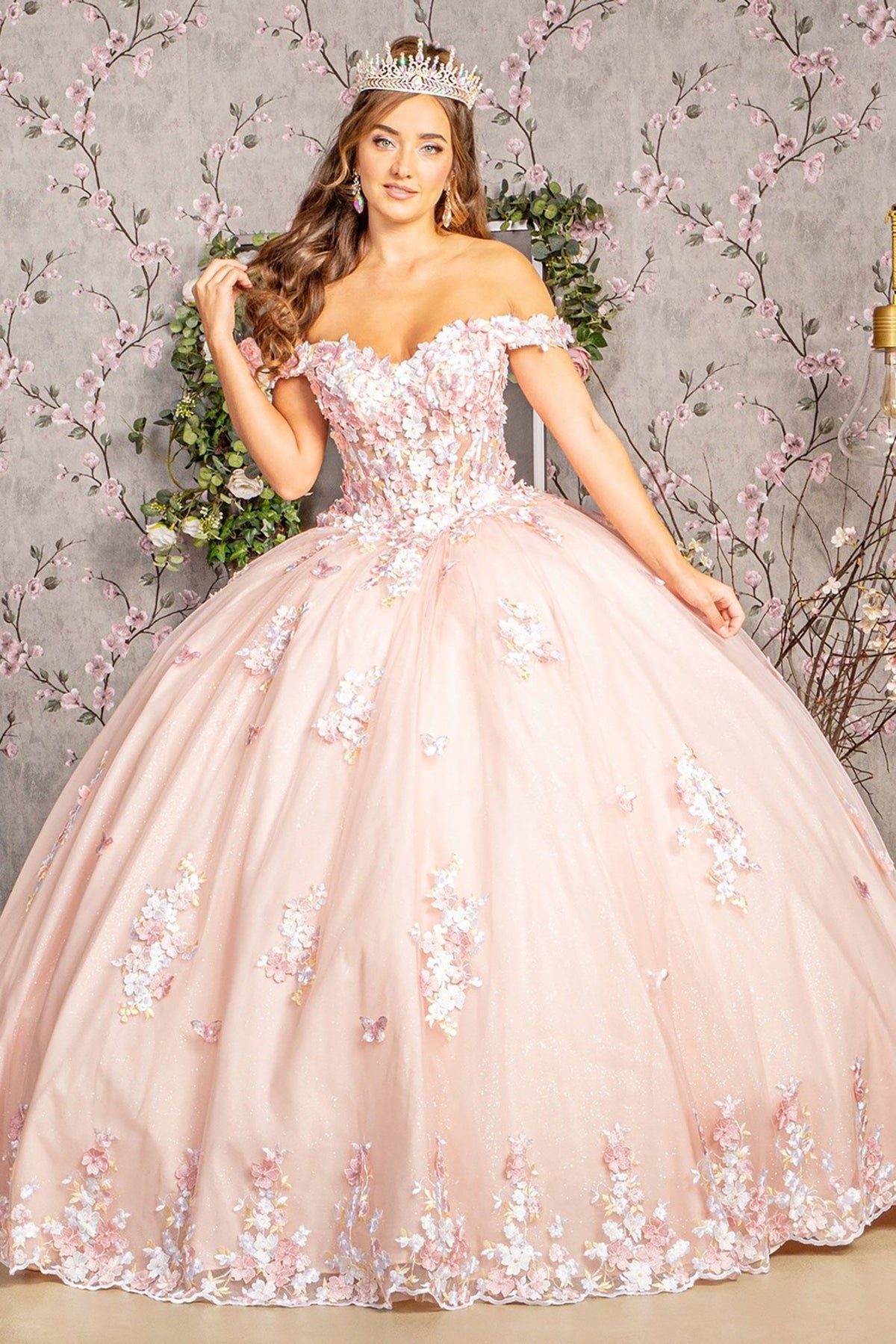 Front view presents blush quinceañera dress with 3D floral appliques, jewel details and long train.