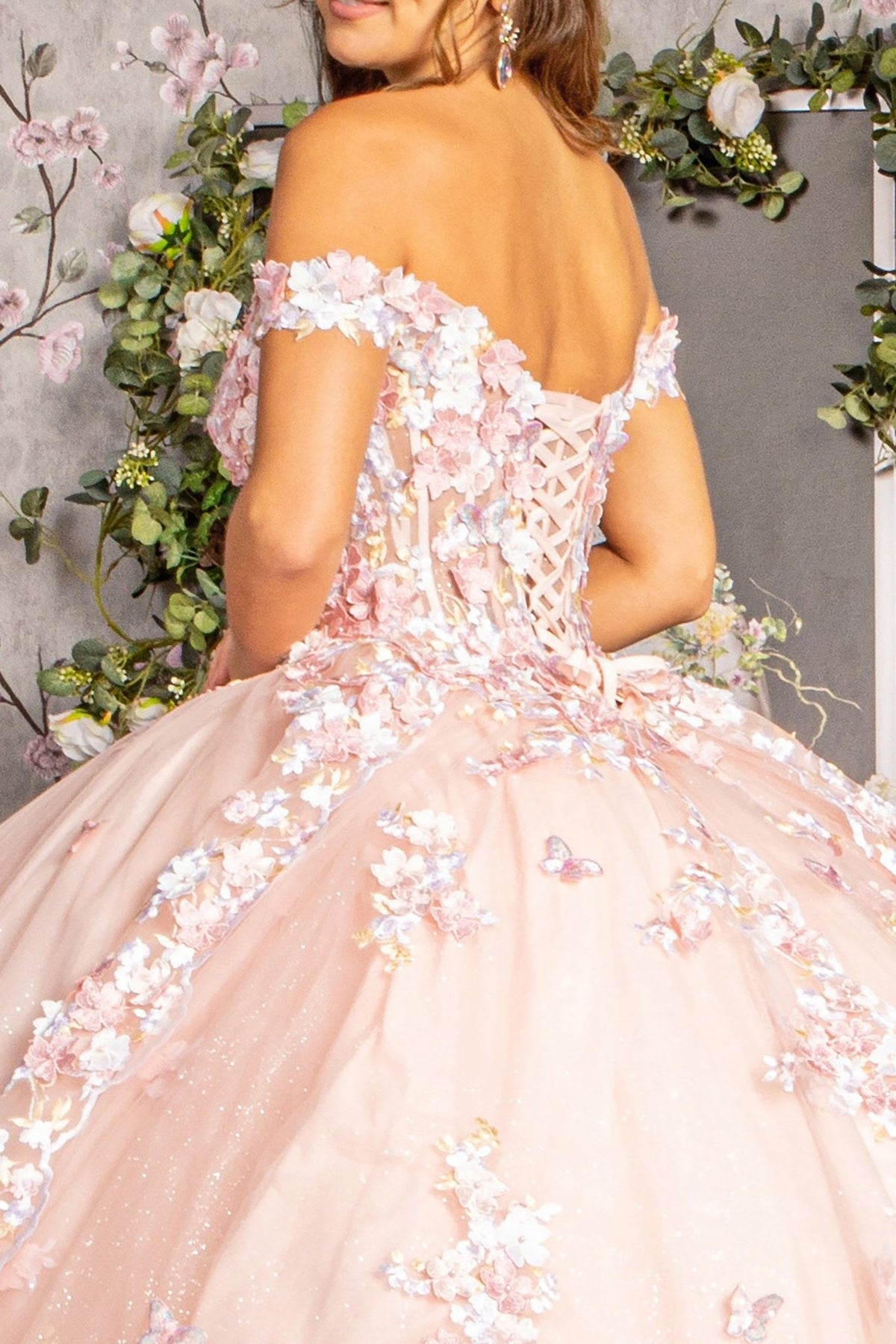 Back detail shows a blush quinceañera dress with floral appliques, jewel details and long train.