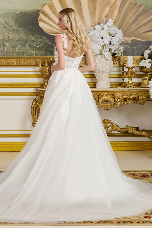 Woman in a white wedding dress standing in an ornate room with gold accents and decorative mirror.