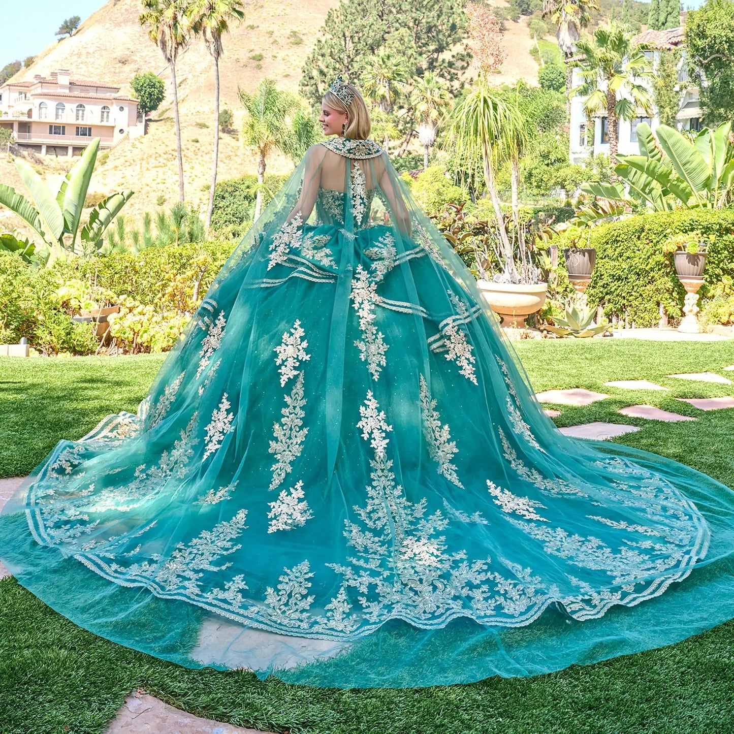 Back view of a woman wearing green quinceañera dress gold sequin embroidery strapless corset ruffled tulle skirt garden setting
