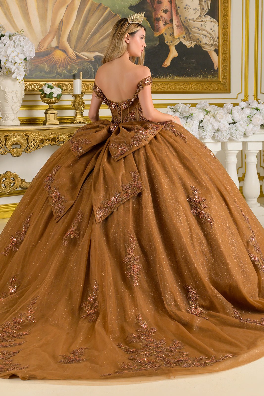 Brown ball gown with intricate detailing in a decorated room.
