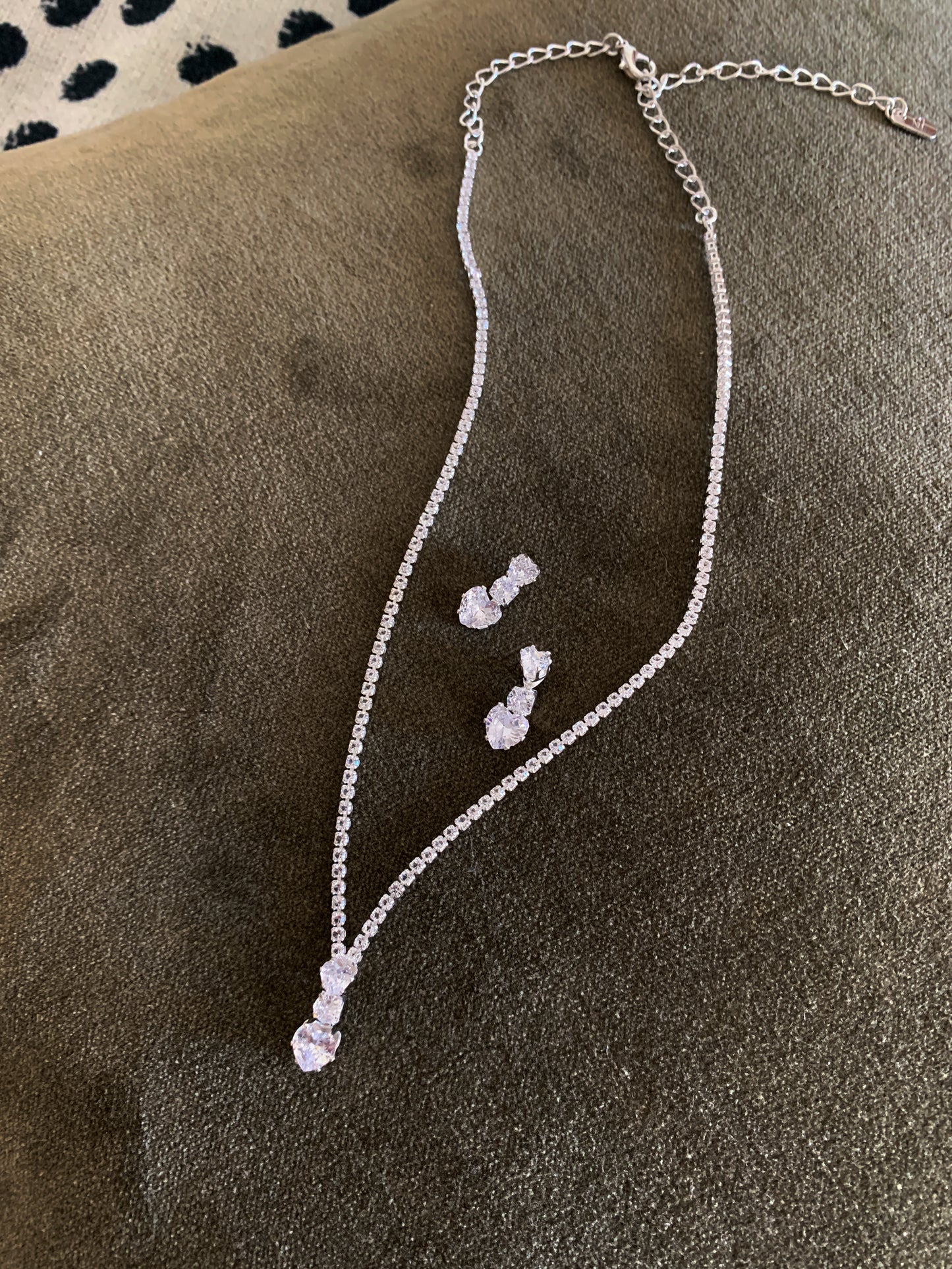Silver necklace and earrings on a textured surface