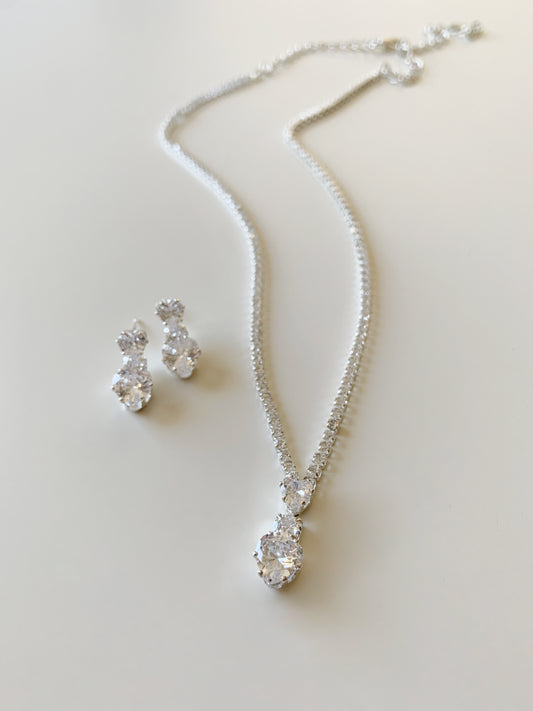 Silver necklace and earrings on a light background