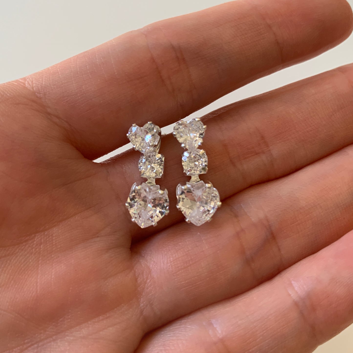 full rhinestone earrings held in a hand against a neutral background