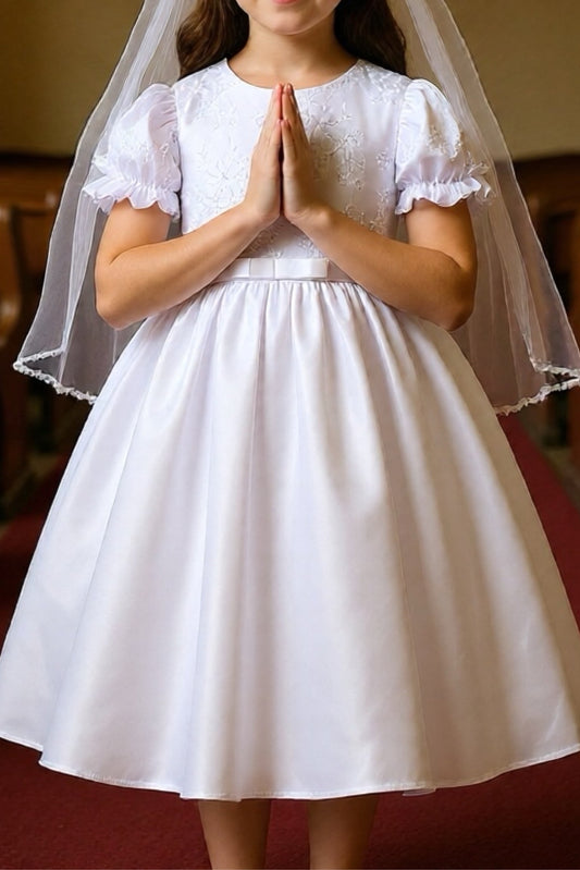 Young girl in a white dress with a veil standing in a church.