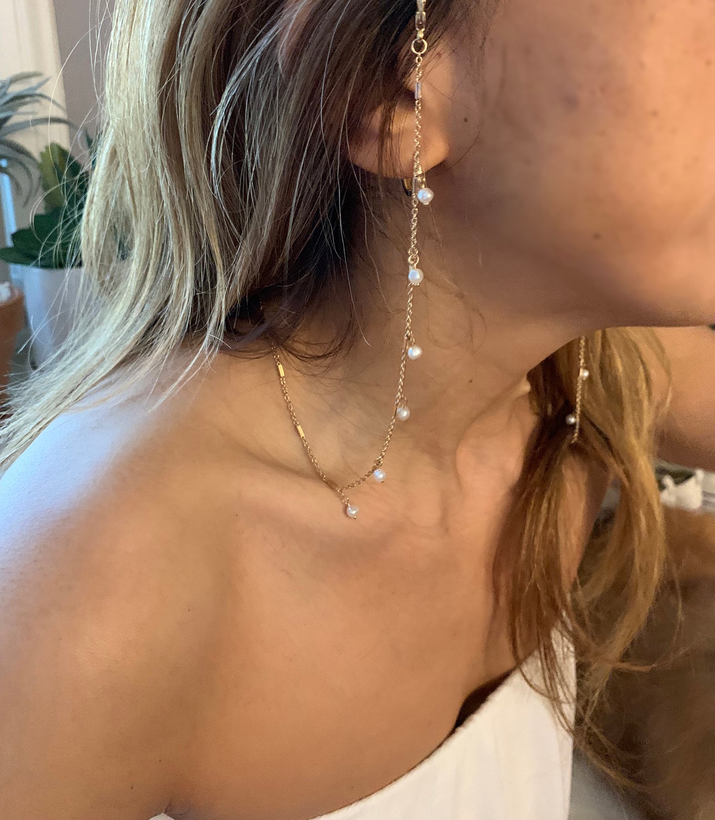 a person wearing eye wear gold chain necklace with pearls