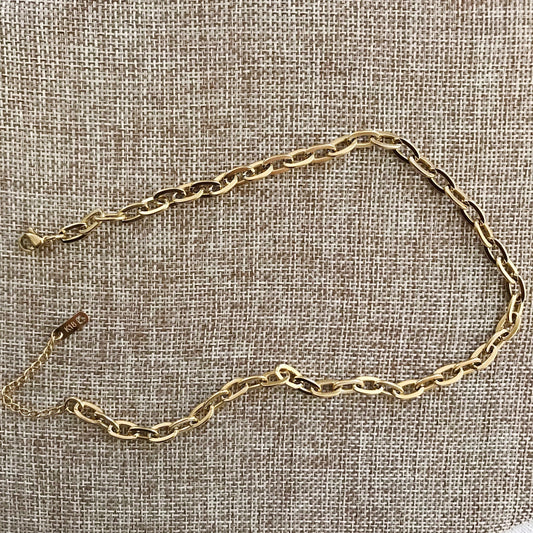 Gold chain necklace on a textured beige fabric background