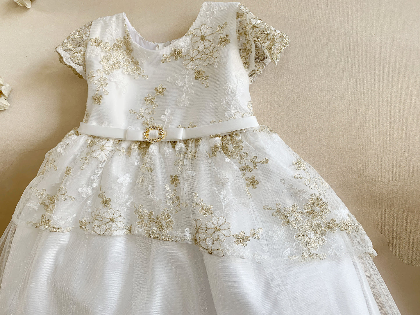 White dress with gold floral embroidery on a beige background