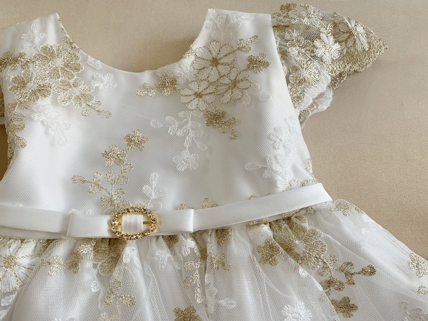 White dress with gold floral embroidery on a beige background